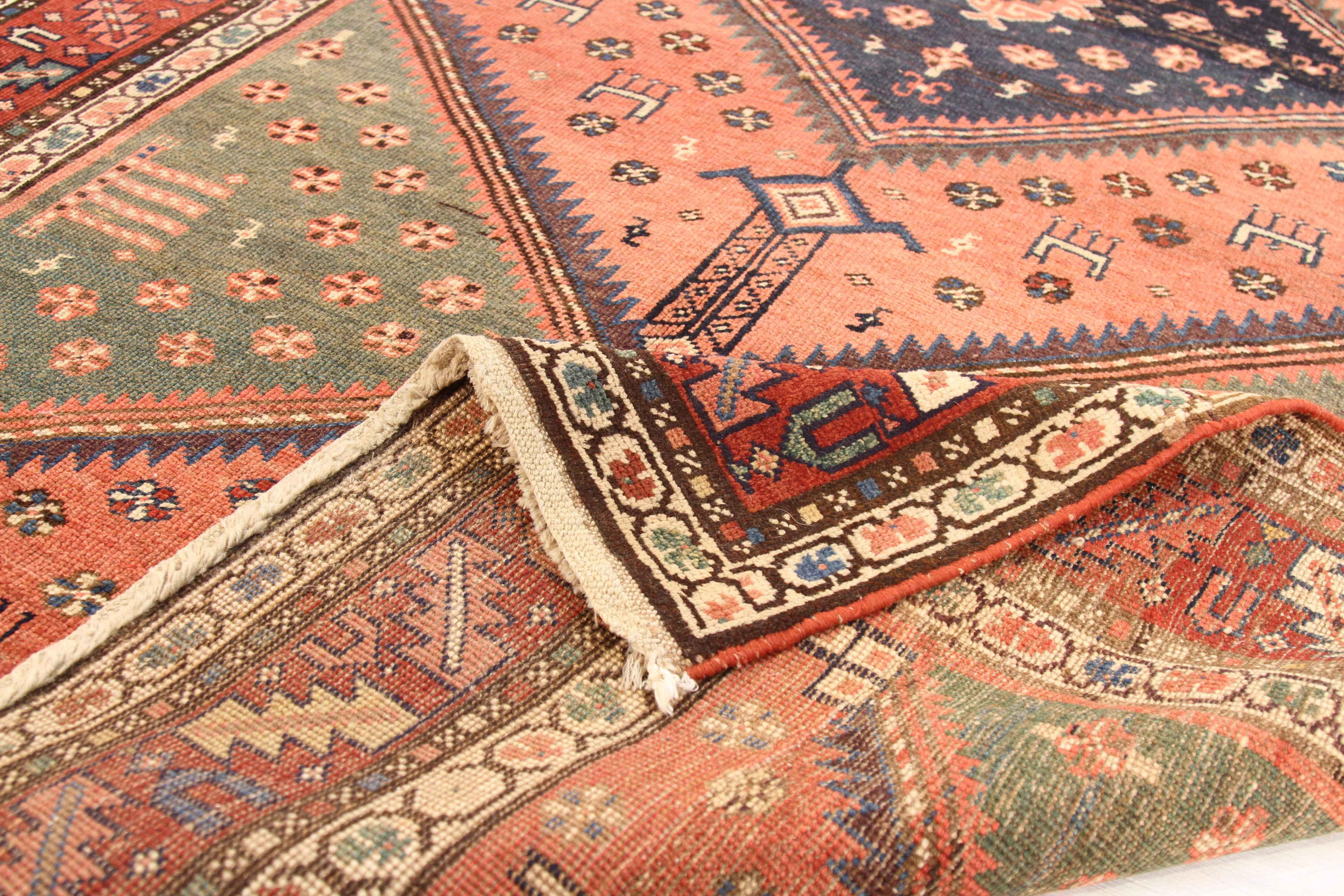 Tapis persan antique des années 1950 tissé à la main à partir de laine exquise et de teintures à base de plantes 100 % biologiques. Son champ central présente de grands triangles multicolores et de minuscules motifs géométriques. Un brillant mélange