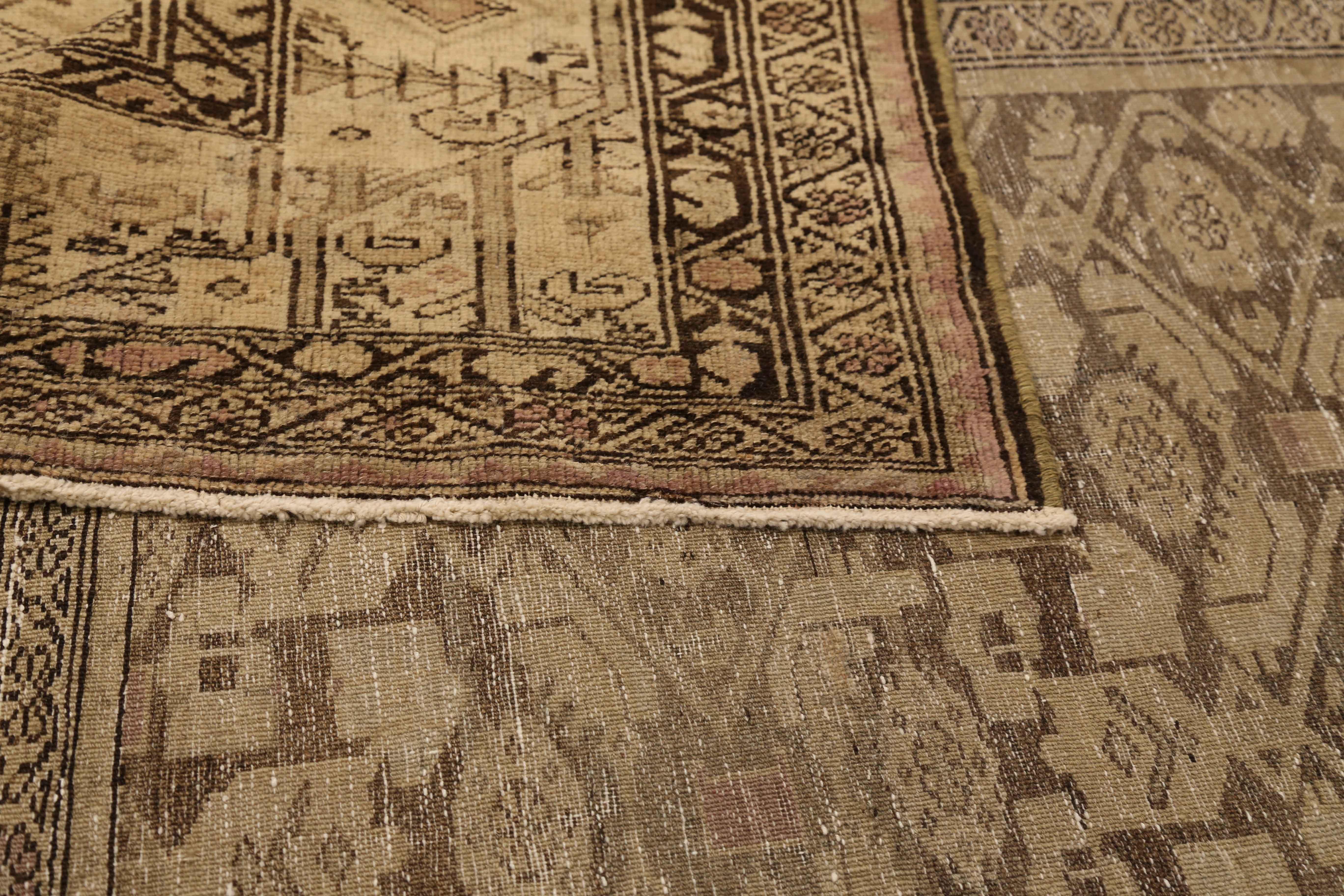 Antique Persian rug made from high grade wool and vegetable dyes. Created in the 1930s, this beautiful rug has an earthy and rustic appeal due to the mix of beige and black with hints of green and pink. It features incredible floral patterns that