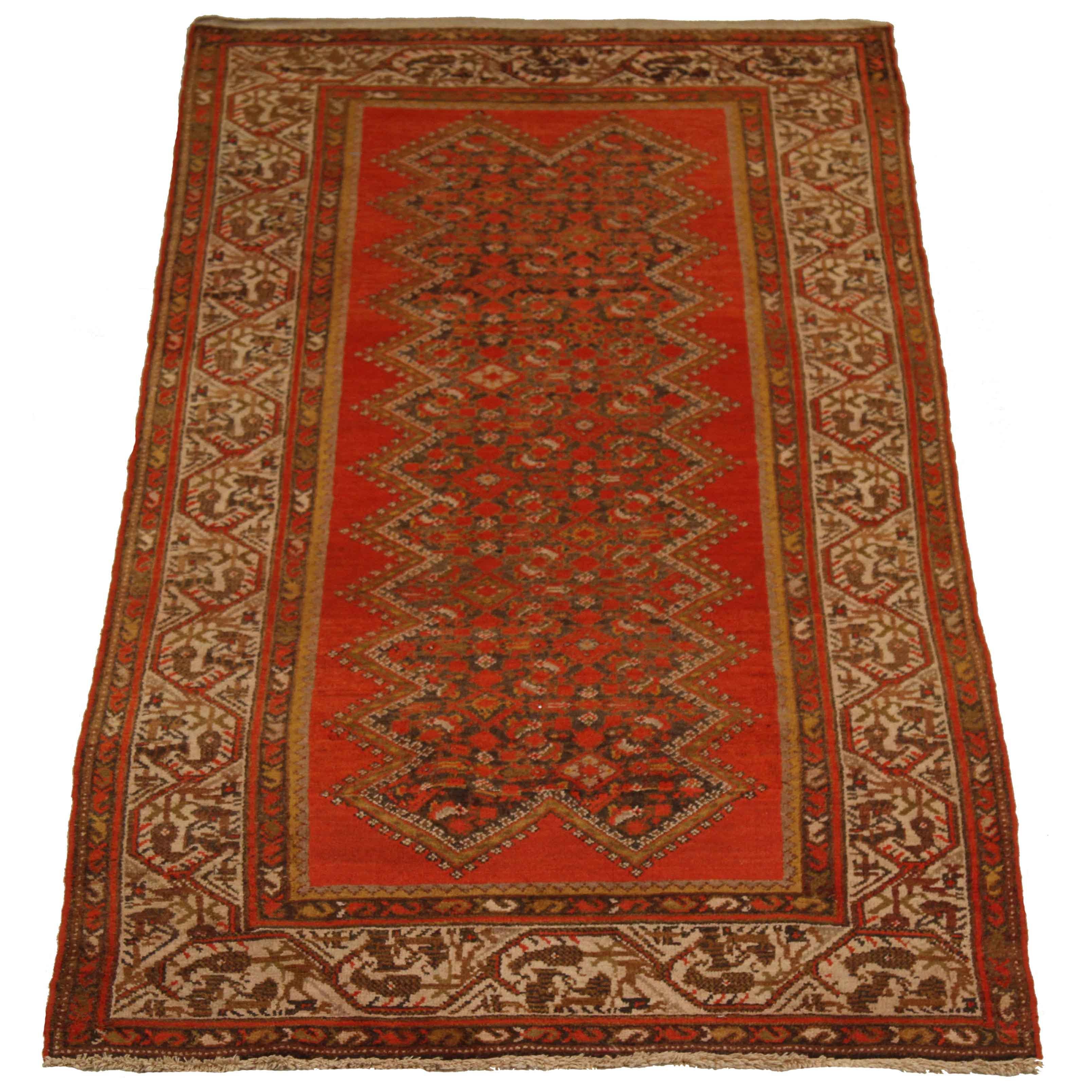 Made of fine wool and handwoven using techniques mastered by Malayer weavers, this antique Persian rug showcases a wonderful fusion of nature-inspired patterns and geometric details. It’s colored in deep red, brown, ivory and yellow which speaks the