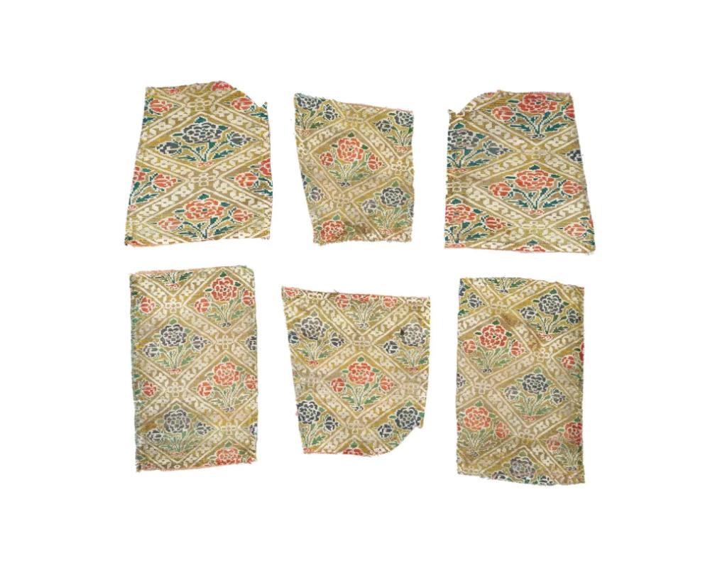 A group of three antique Persian Iranian Safavid dynasty hand woven embroidered textile fragments, circa 17th century, showcase the dynastys intricate craftsmanship. The design features stylized flowers in a diamond lattice, with a rich yet subtle