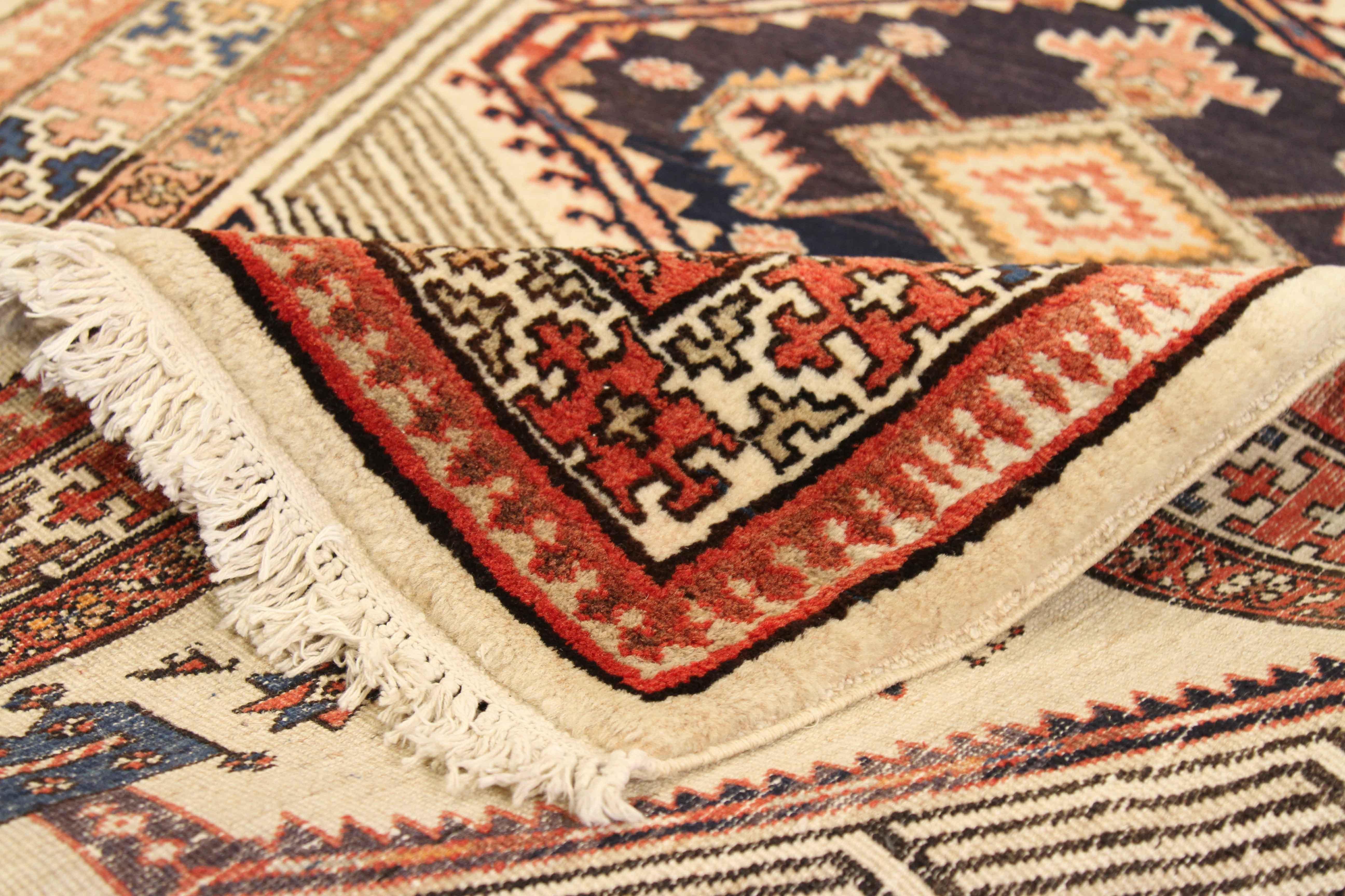 Antique Persian rug made of wool and bright natural dyes handwoven in the 1950s. It showcases a highly intricate tribal pattern using techniques favored by rug makers in Sarab. For color, the field’s foundation is ivory layered with black, navy, and