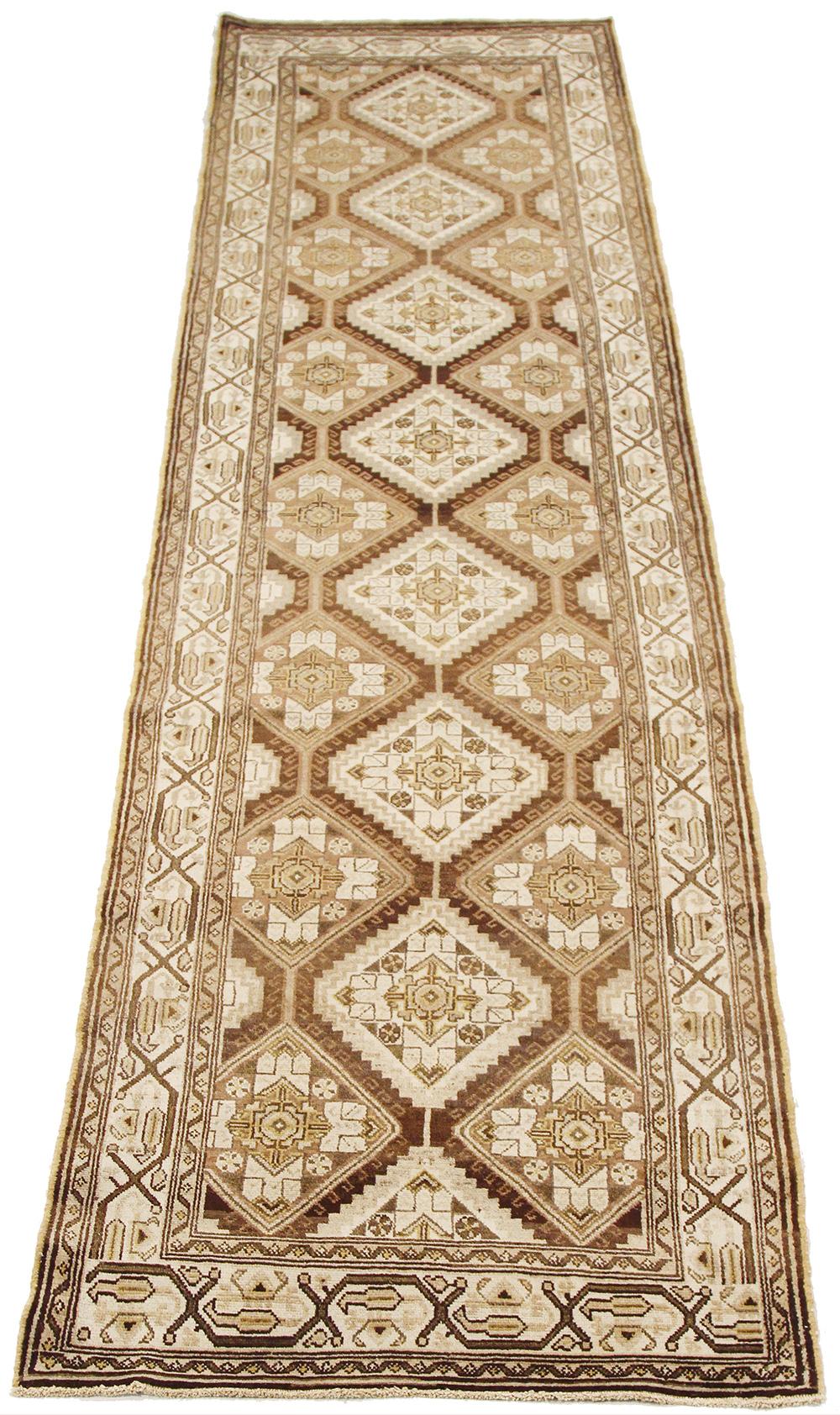 Antique Persian runner rug handwoven from the finest sheep’s wool and colored with all-natural vegetable dyes that are safe for humans and pets. It’s a traditional Sarab design featuring medallion details in ivory and beige over a brown field. It