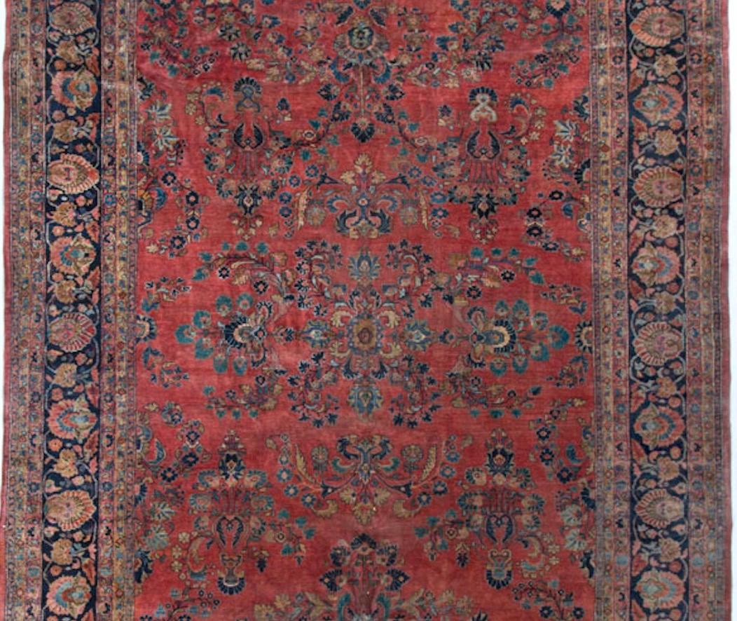 Typical Sarouk colors in this handmade rug, circa 1900s. The soft terracotta ground filled with floral designs is surrounded by a strong navy border that sets the rug of so well. This Sarouk as is common with rugs from this area, is a very thick and