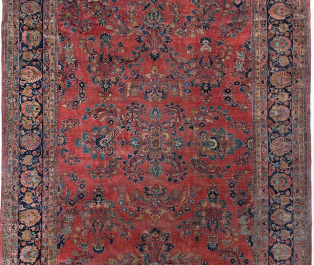 Typische Sarouk-Farben in diesem handgefertigten Teppich, um 1900. Der weiche Terrakotta-Grund mit floralen Mustern ist von einer kräftigen marineblauen Bordüre umgeben, die den Teppich besonders gut zur Geltung bringt. Dieser Sarouk ist, wie bei