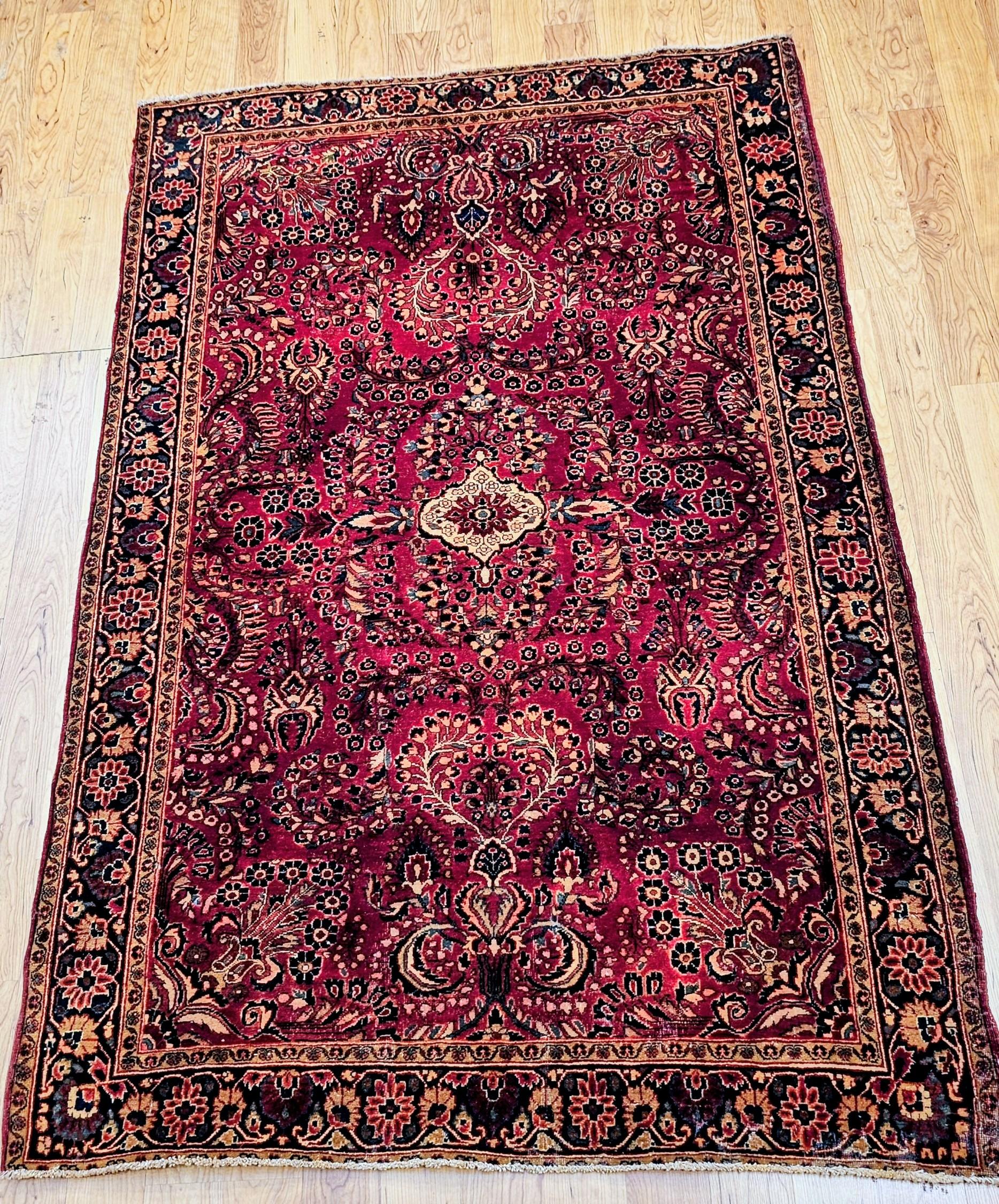 Un élégant tapis sarouk persan ancien du premier quart du 20e siècle, tissé à la main avec un savoir-faire exceptionnel et conservé en excellent état avec un poil plein et doux. Le tapis présente un motif floral raffiné de vase allover entourant un