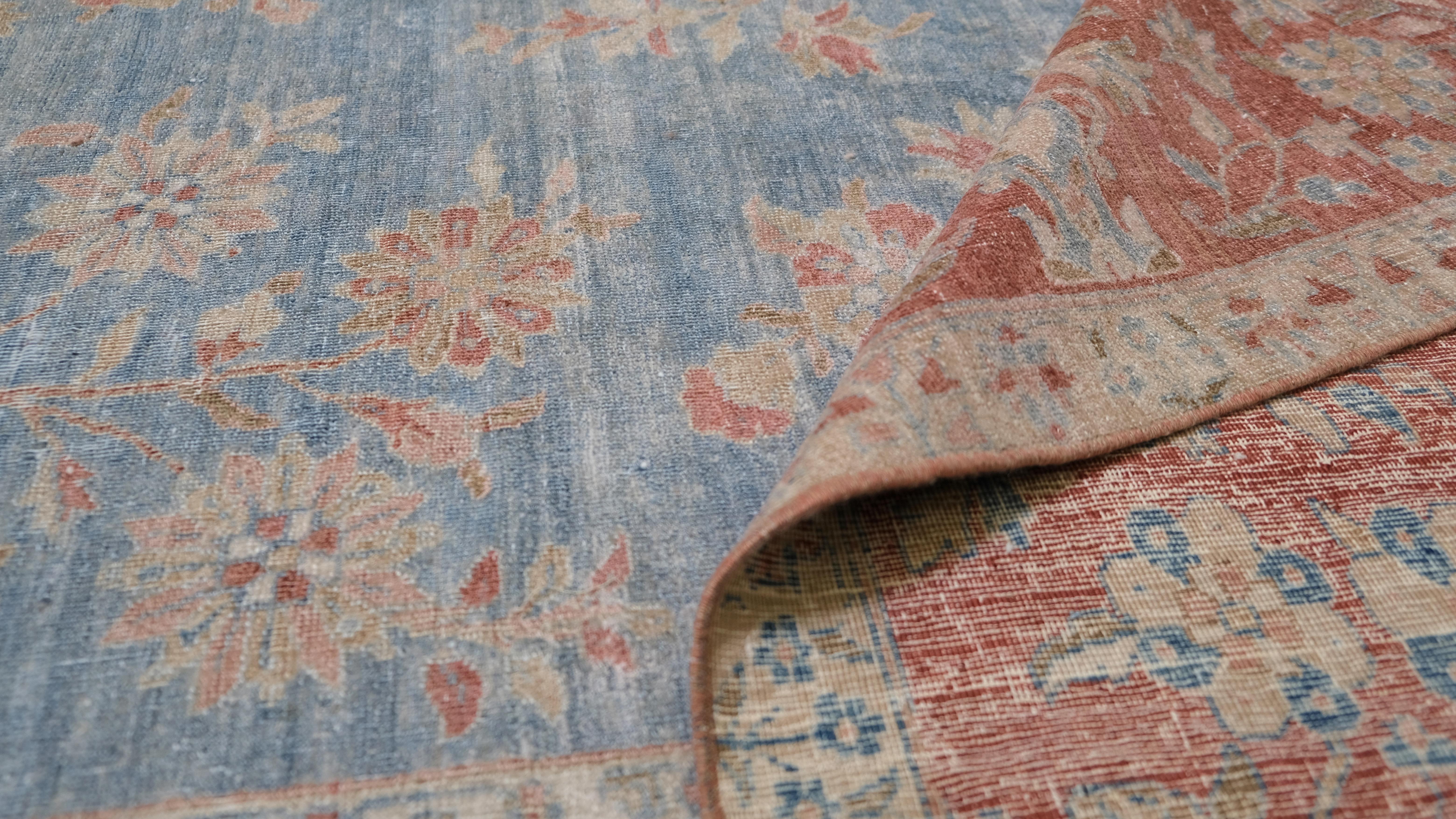 Dieser exquisite antike Teppich ist ein Meisterwerk traditioneller iranischer Handwerkskunst. Die handgeknüpfte Wolle garantiert Haltbarkeit und Schönheit. Der Teppich zeigt ein kompliziertes Blumenmotiv auf einem zartblauen Feld, das elegant von