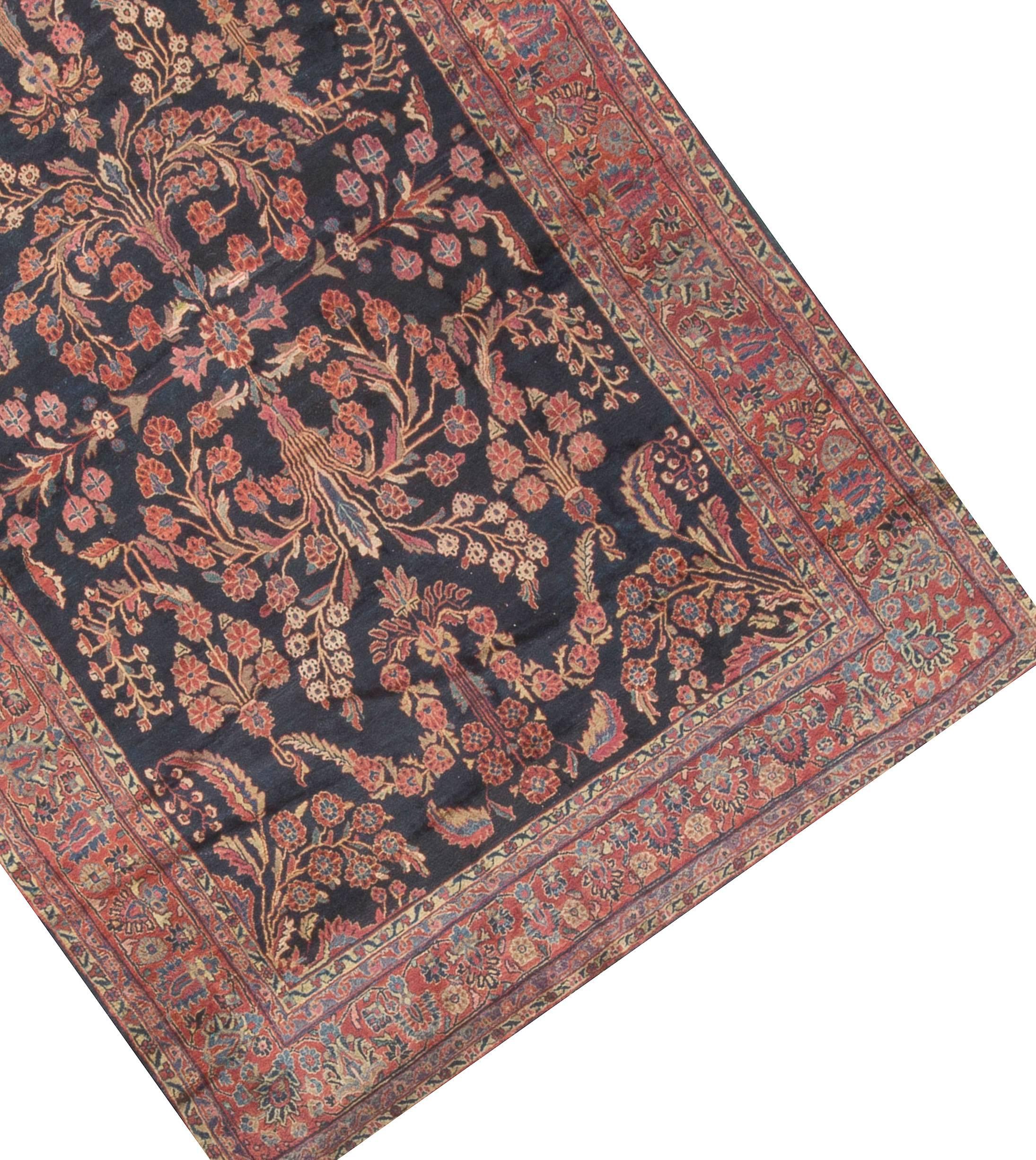 This antique Sarouk Feraghan has a bold look. The navy field filled with trailing floral designs is enclosed by four guard borders and a main border in soft reds, blues and ivory all repeating the floral design that together enhance the feeling of