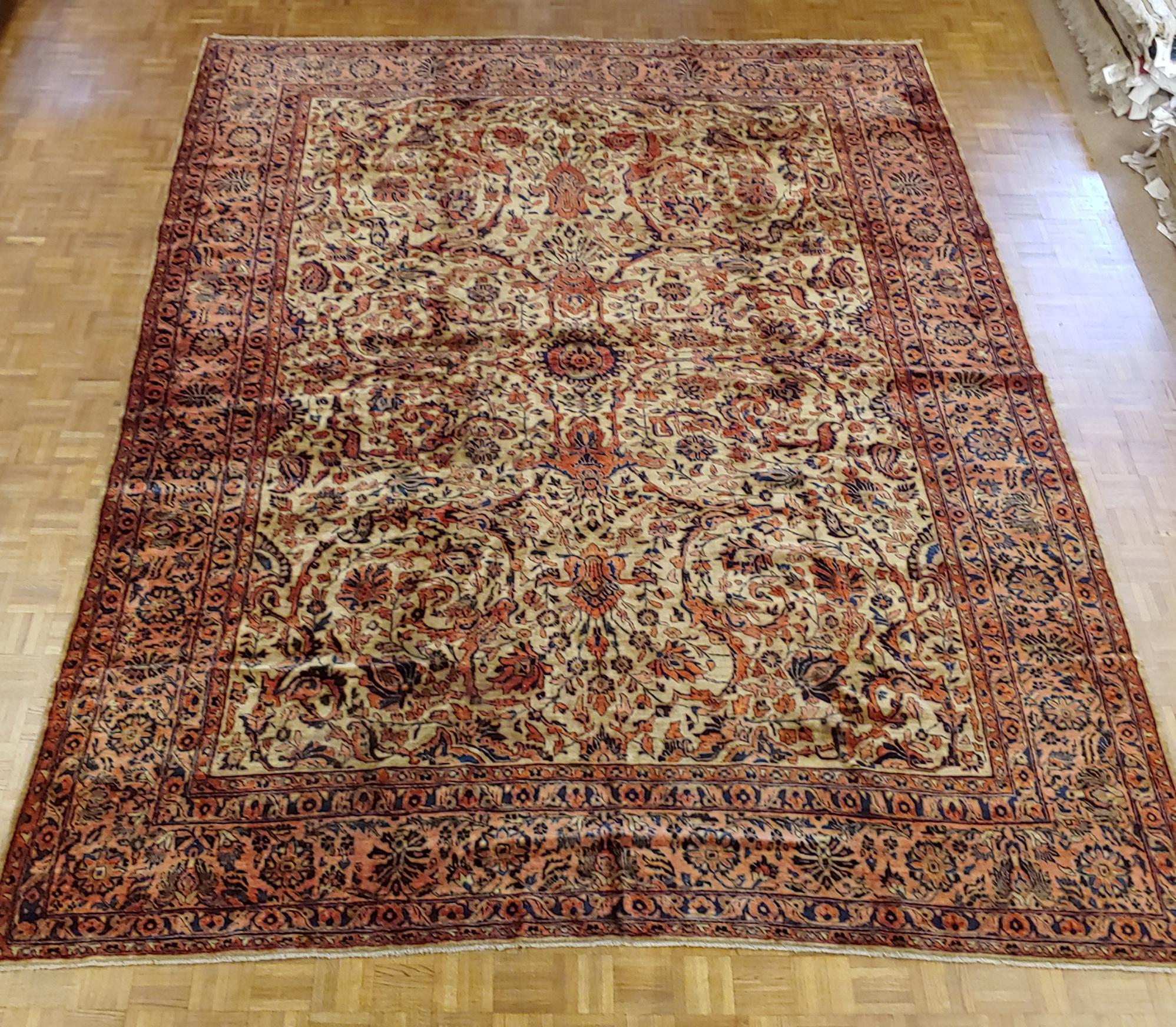 This is a wonderful and luxurious antique Persian Sarouk with a rare light gold field decorated with a detached floral motive in blues and reds is encased in a impressive salmon colored floral border. The wool feels like silk. It is 8-9 x 11-5 and