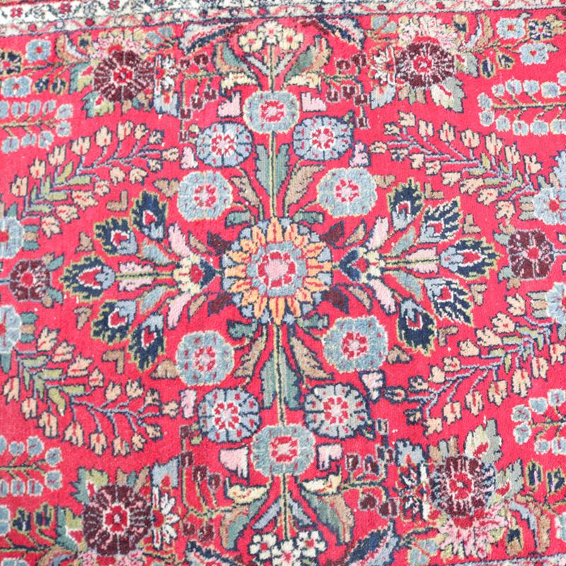 An antique Persian Sarouk oriental rug offers wool construction with central floral medallion and all-over floral spray on red ground, circa 1930

Measures: 81