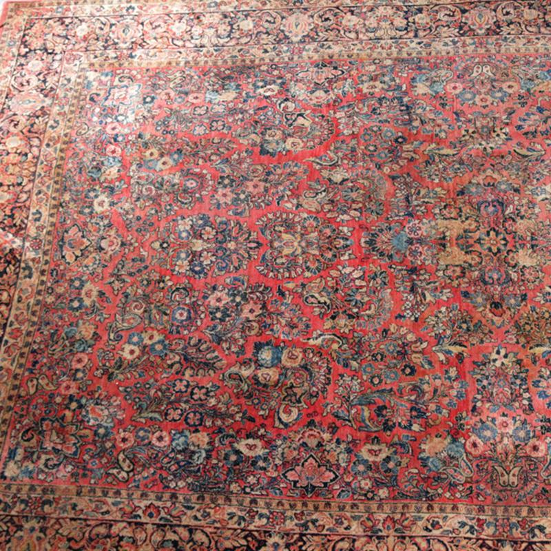 An antique Persian Sarouk room size oriental rug offers wool construction with central medallion and all-over floral spray on salmon ground, circa 1920

Measures: 184