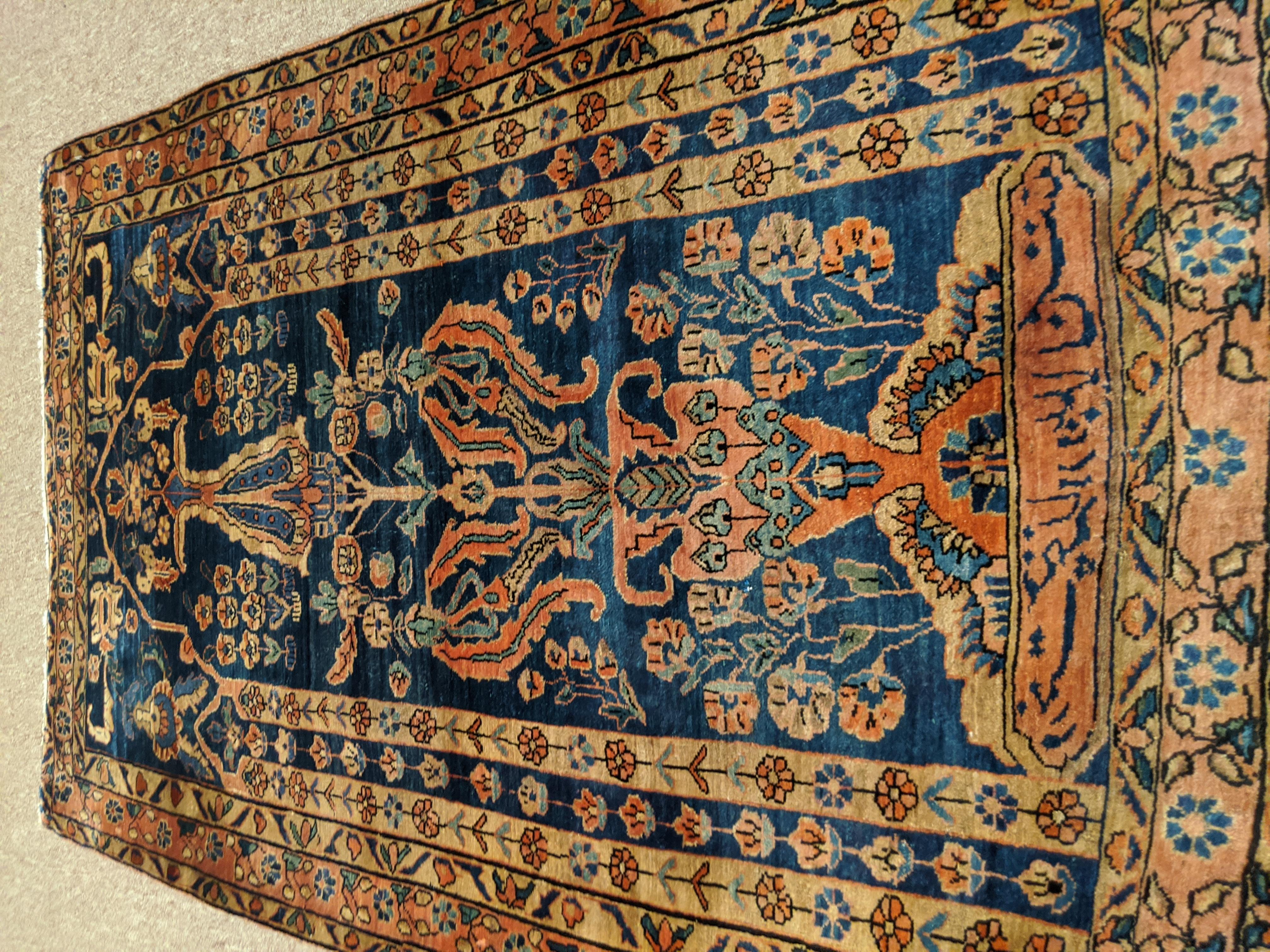 Persian Sarouk with an all-over field design with a medium blue background and a rust border. The field is one directional vase design decorated with vines, tendrills and flowers in light blue, gold and teal. The wool is so soft that it feels like