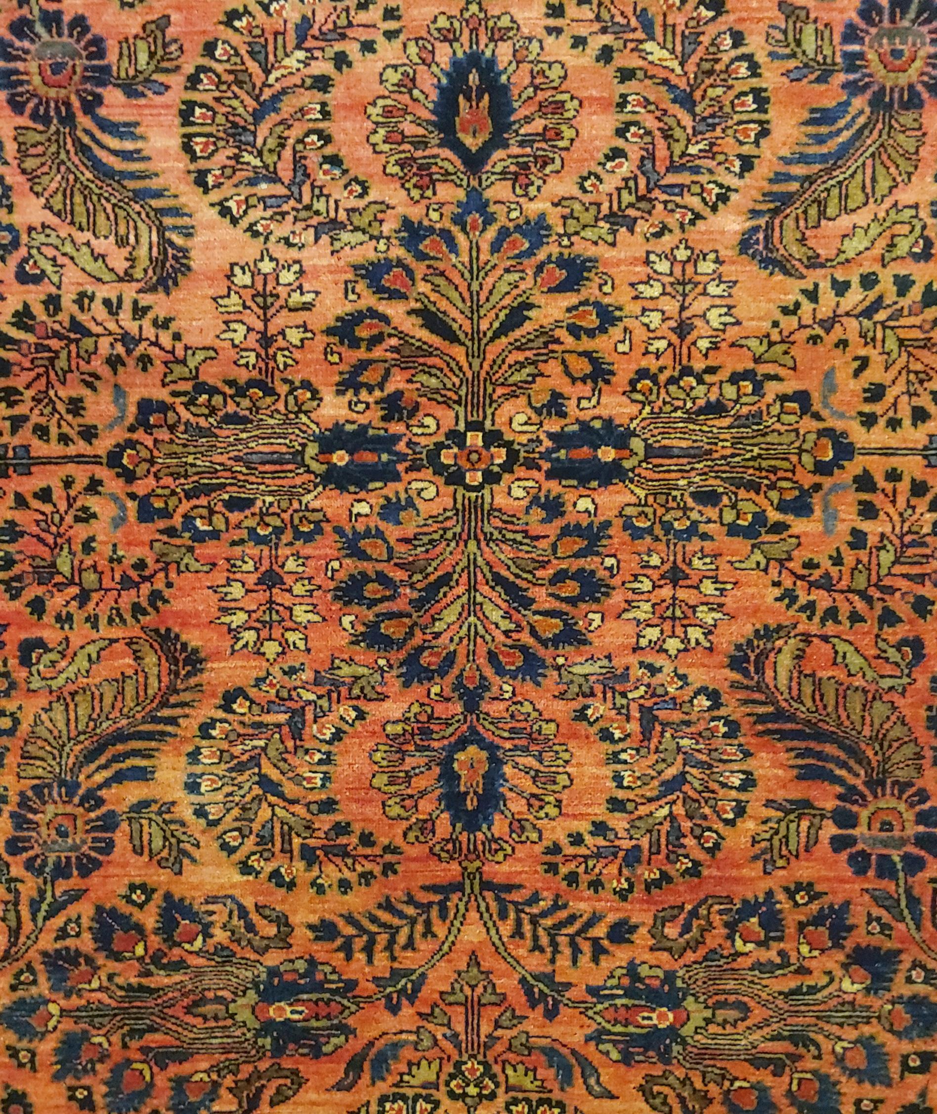 Persian Sarouk with an all-over field design with a rust background and a navy border. The field is decorated with vines, tendrills and flowers in light blue, gold and teal. The wool is so soft that it feels like silk. It is a 4-3x6-7 and is circa