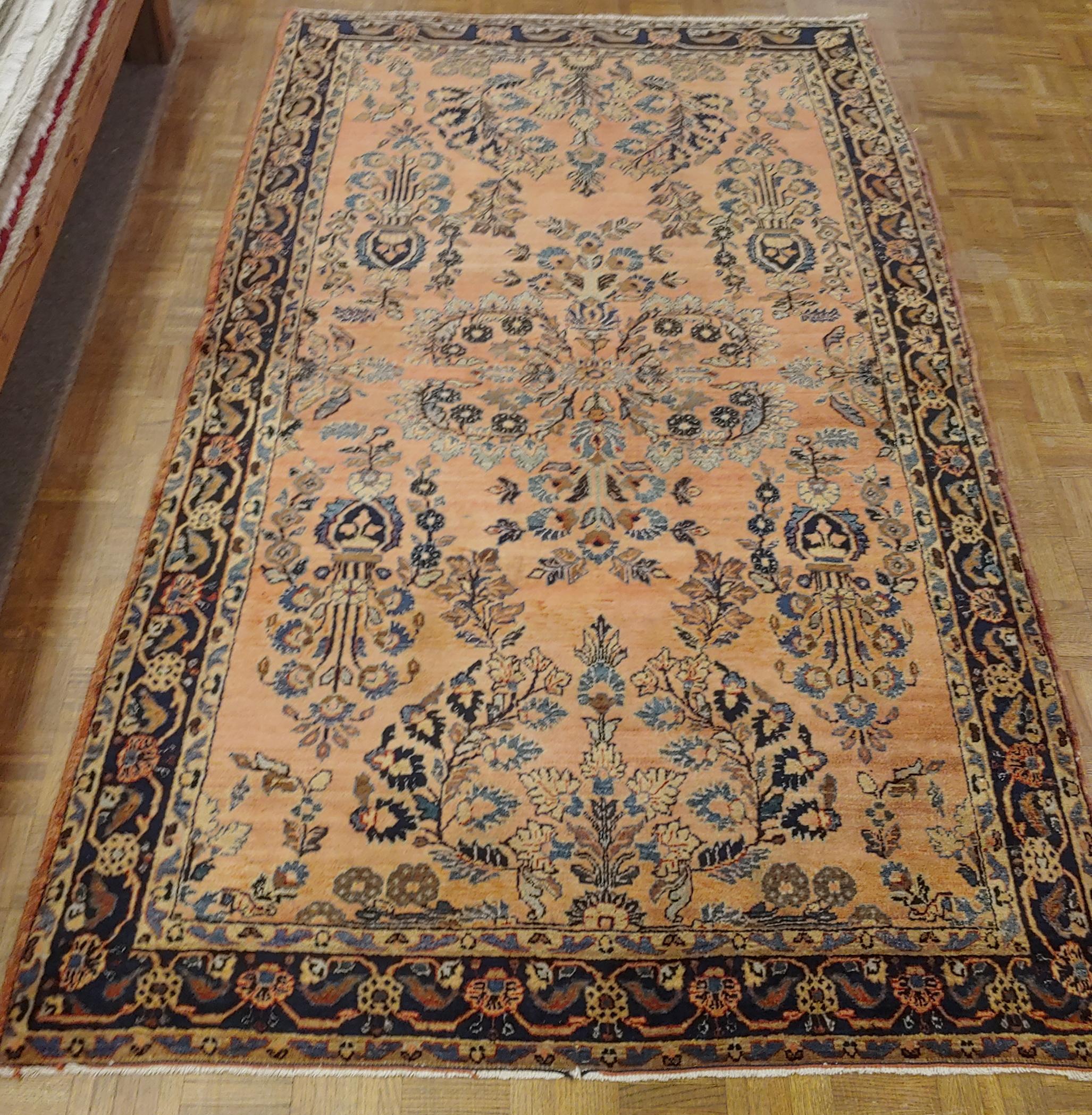 Persian Sarouk with an all-over field design with a rust background and a navy border. The field is decorated with vines, tendrills and flowers in light blue, gold and teal. The wool is so soft that it feels like silk. It is a 4-6x6-6 and is circa