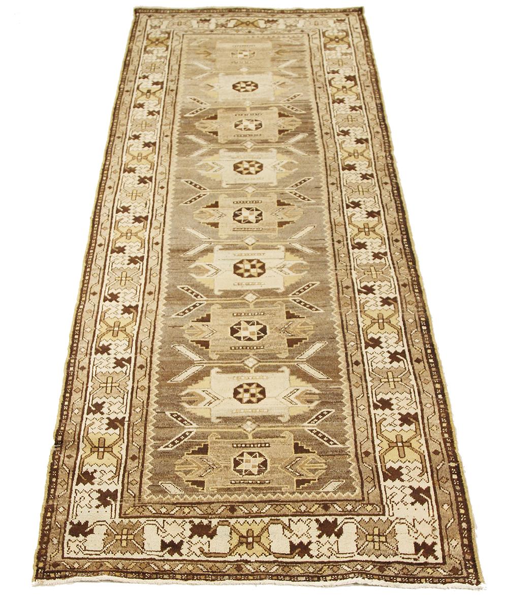 Alfombra persa antigua tejida a mano con la mejor lana de oveja y teñida con tintes vegetales naturales inocuos para las personas y los animales domésticos. Es un diseño Saveh tradicional realzado por motivos geométricos marrones y marfil. Es una
