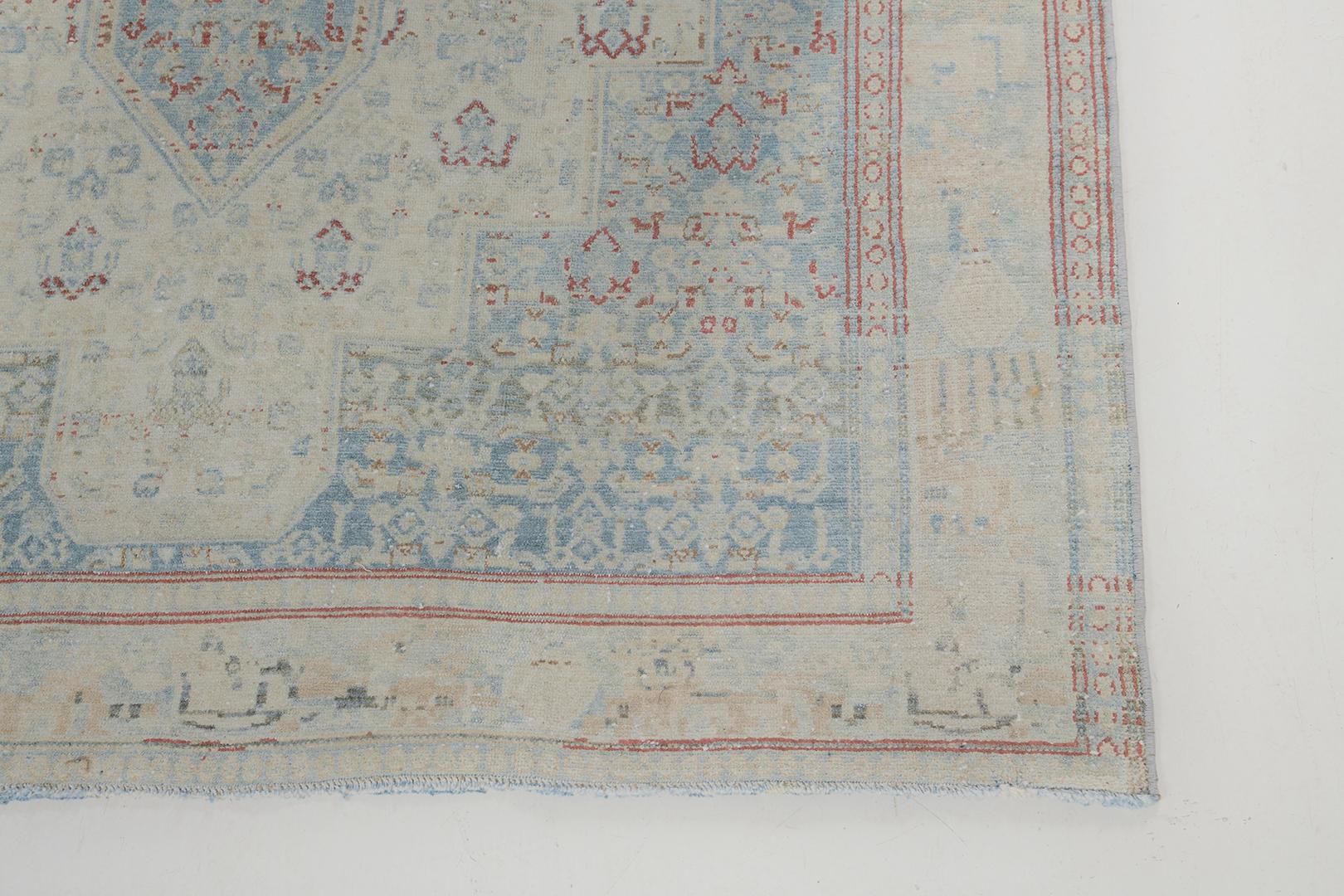 Featuring a phenomenal array of floral forms, leafy tendrils and lush palmettes, this breathtaking Antique Persian Seneh rug. Through the use of muted neutral color scheme of beige, dusty blue and hints of crimson, the embellished dainty floral