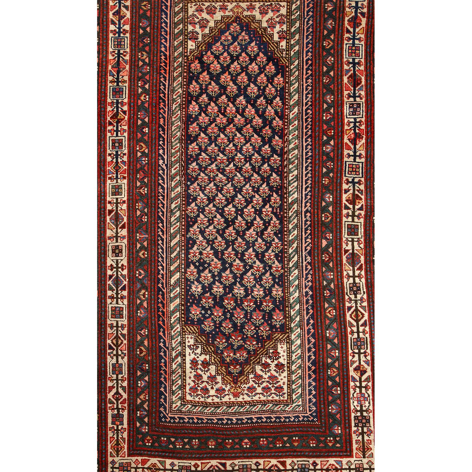This antique Persian Senneh carpet in pure handspun wool and vegetable dyes circa 1900 features a floral patterned central medallion and field with multiple borders of alternating geometric designs. Bright cream colored wools and deep indigo