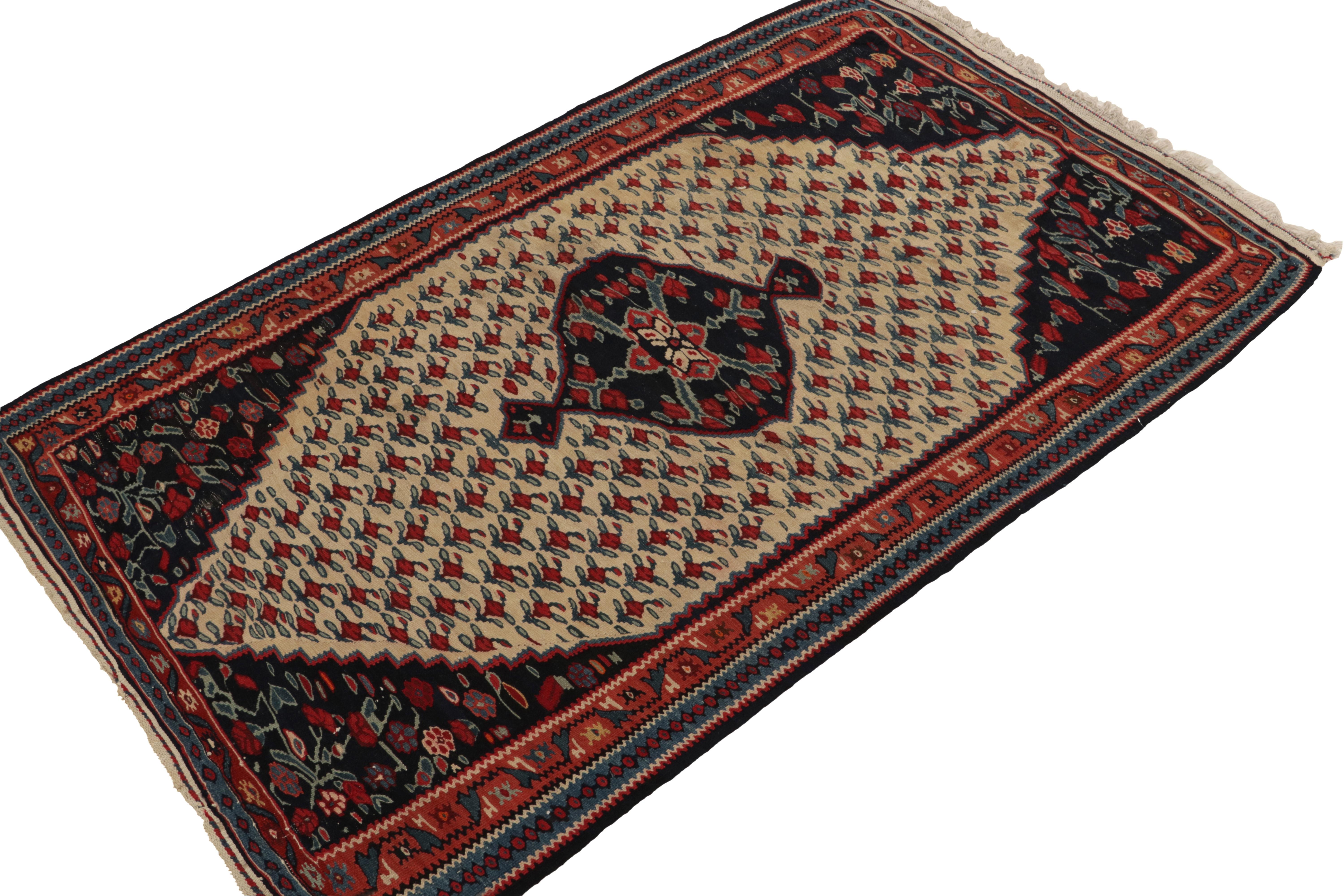 Handwoven in wool, a 3x5 antique Senneh Kilim rug originating circa 1930-1940. This beautiful piece showcases a brilliant floral design distinct from other tribal provenances in persian weaving. Boasting rich tones of red and blue on beige, an