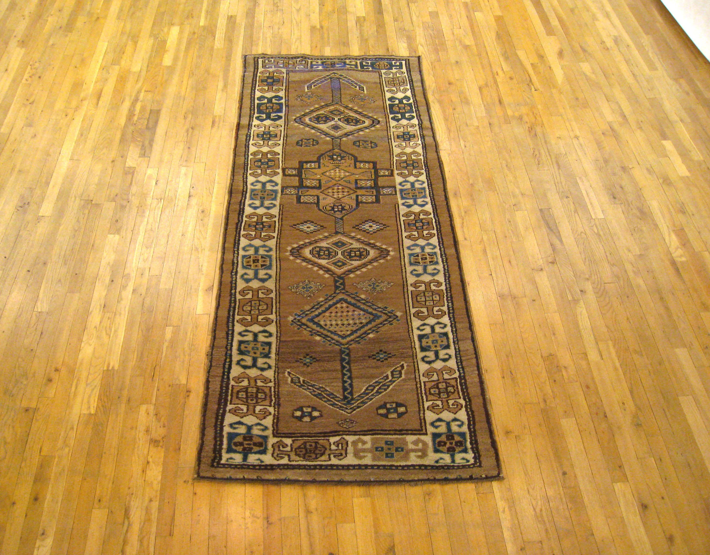 An antique Persian Serab Camel Hair oriental rug, size 8'7 x 3'2, circa 1900. This handsome hand knotted wool carpet is characterized by a tribal design at centre, with several angular medallions leading to an end point in either direction. The dark