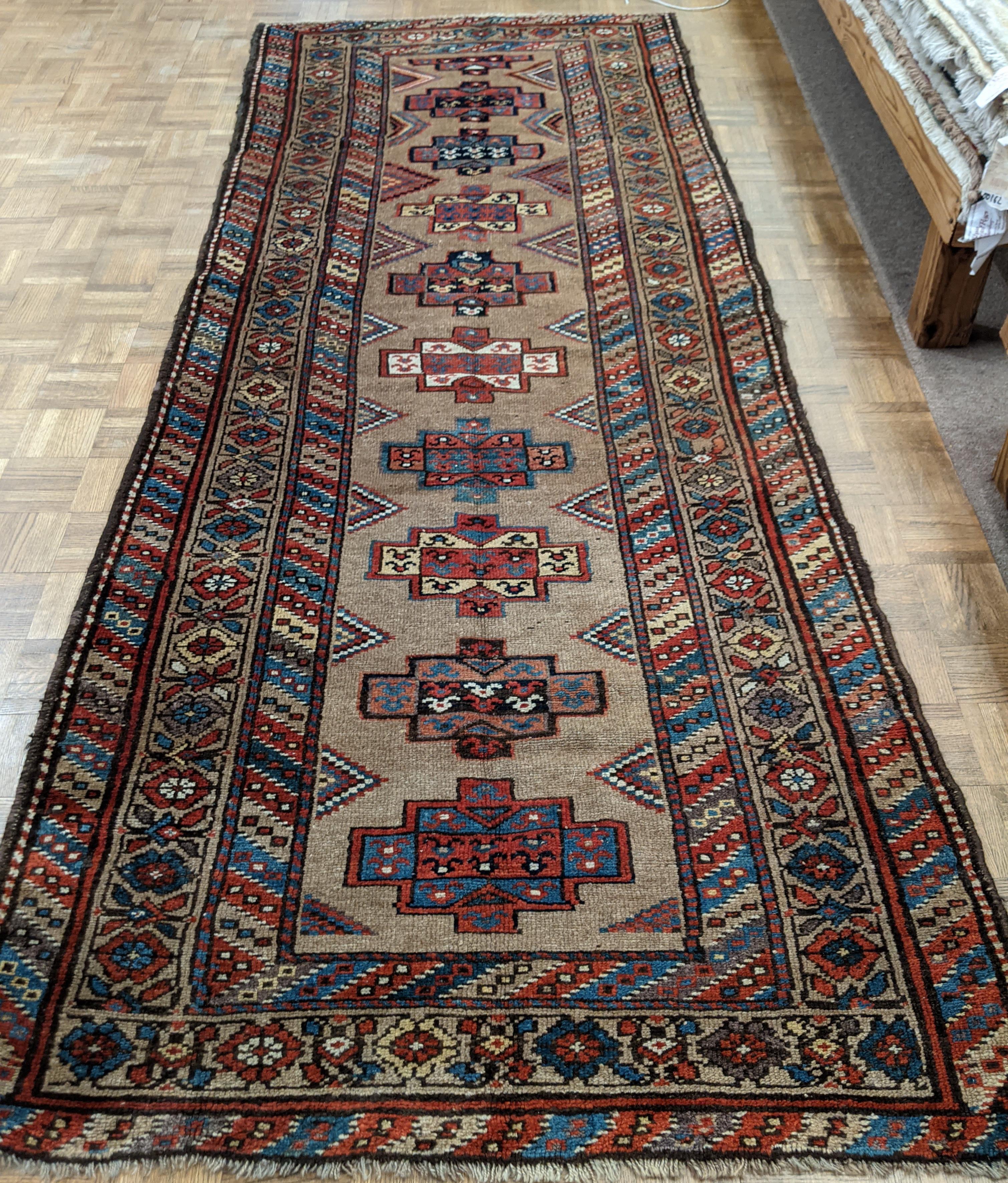 This is a early antique Persian Serab. Serab rugs are known for their geometric design as well as the use of camel color. an aypical Serab motif with the use of a cinnamon rust color is accented on the camel field in a motif similar to Mogan Kazak