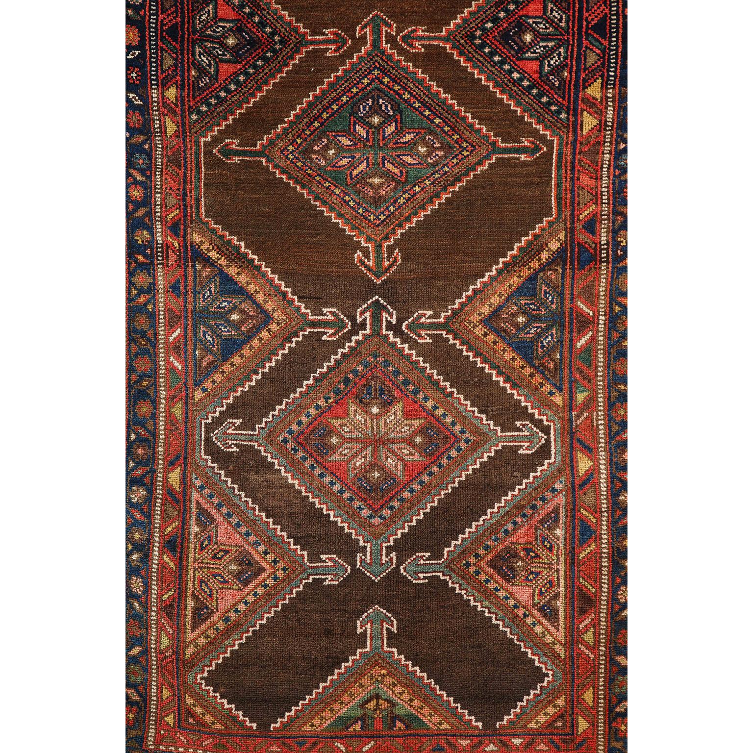 This antique Persian Seraband carpet in pure wool and vegetable dyes circa 1900 features a central mirrored band design with intricately detailed and layered borders. Hand knotted in pure handspun wool upon a woolen warp and weft, its organic design