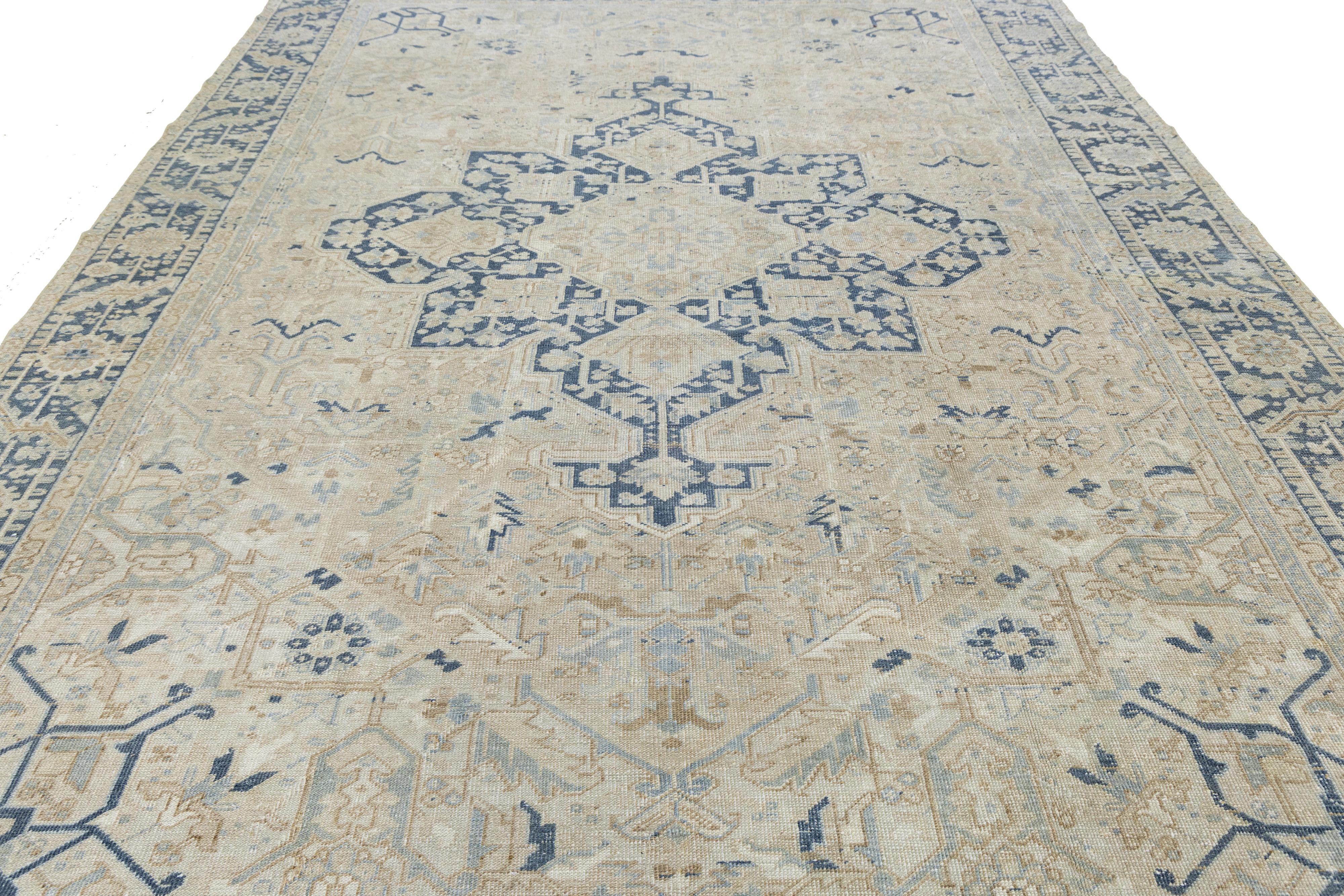 Ce tapis serapi persan antique noué à la main est un magnifique exemple de travail artisanal. Son fond beige chaud présente un médaillon central saisissant, complété par des nuances de bleu dans des motifs géométriques et floraux