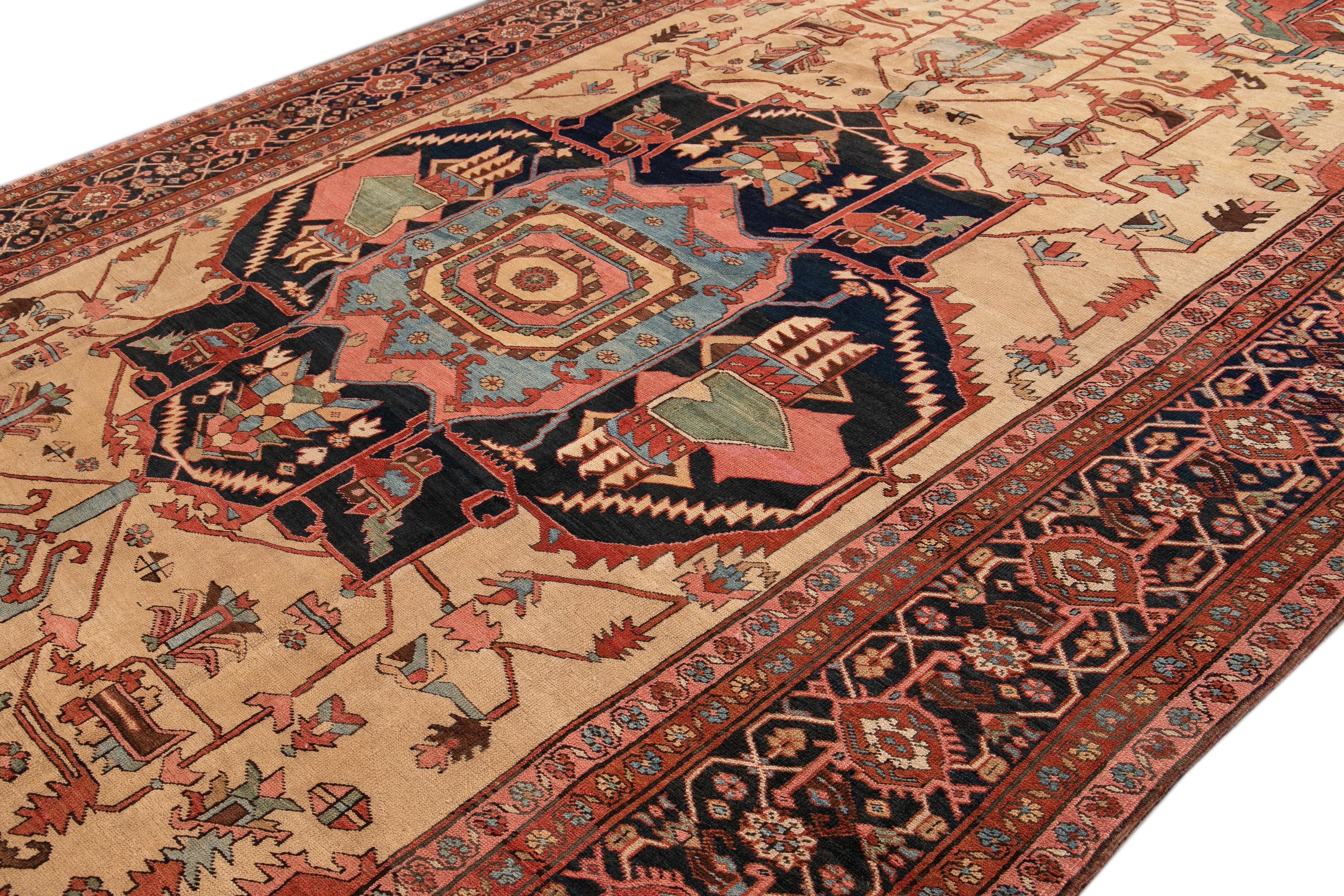 Bellissimo tappeto antico in lana Serapi annodato a mano con campo beige e ruggine. Questo tappeto persiano ha una cornice floreale blu navy e accenti multicolore in uno splendido disegno a medaglione geometrico all-over.

Questo tappeto misura: