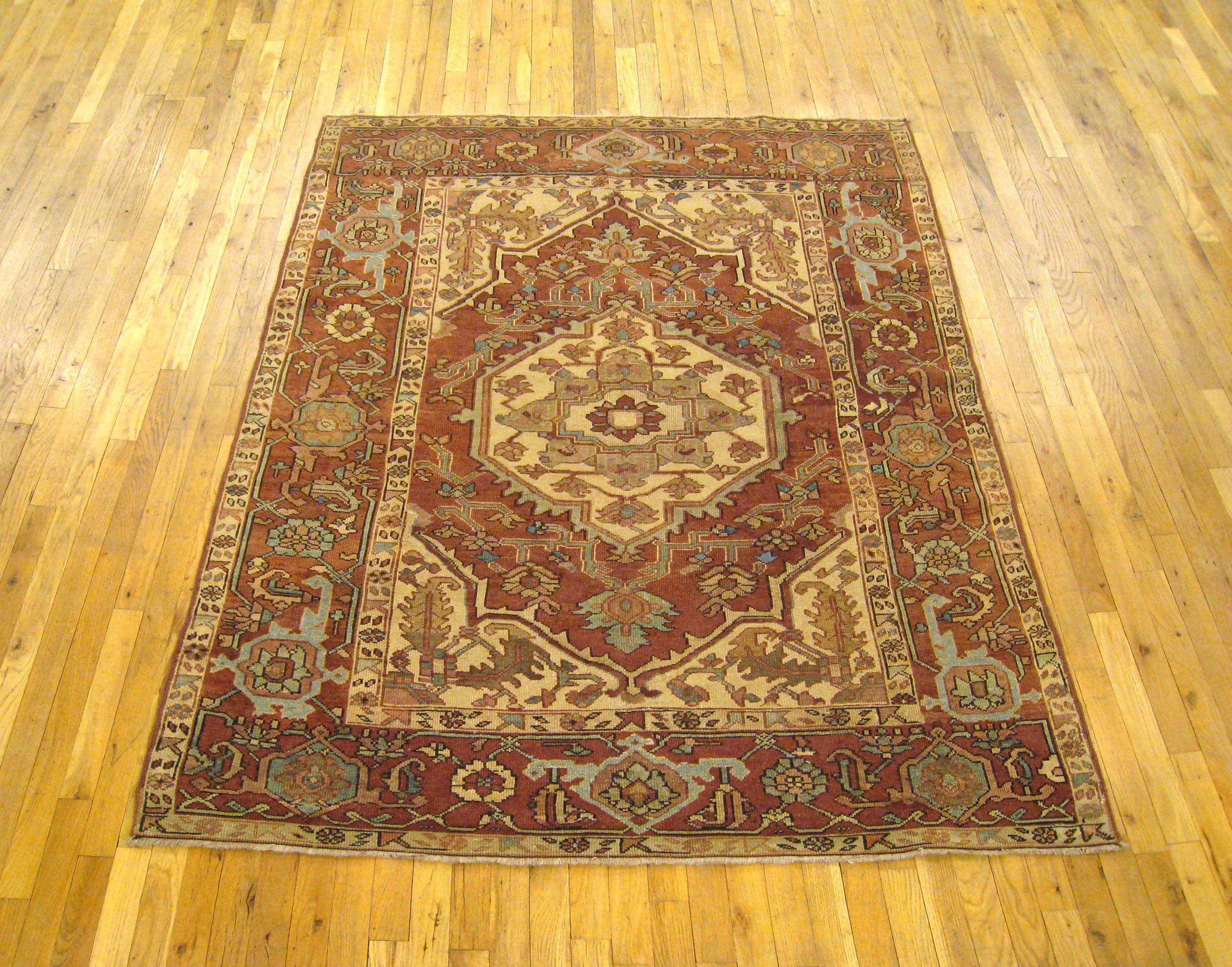 An antique Persian Serapi oriental rug, size 6'2 x 5'0, circa 1900. This handsome hand-knotted wool rug features a rare ivory field at center, with soft reds, light blues, and other earth tones throughout the rest of the carpet. The central field is