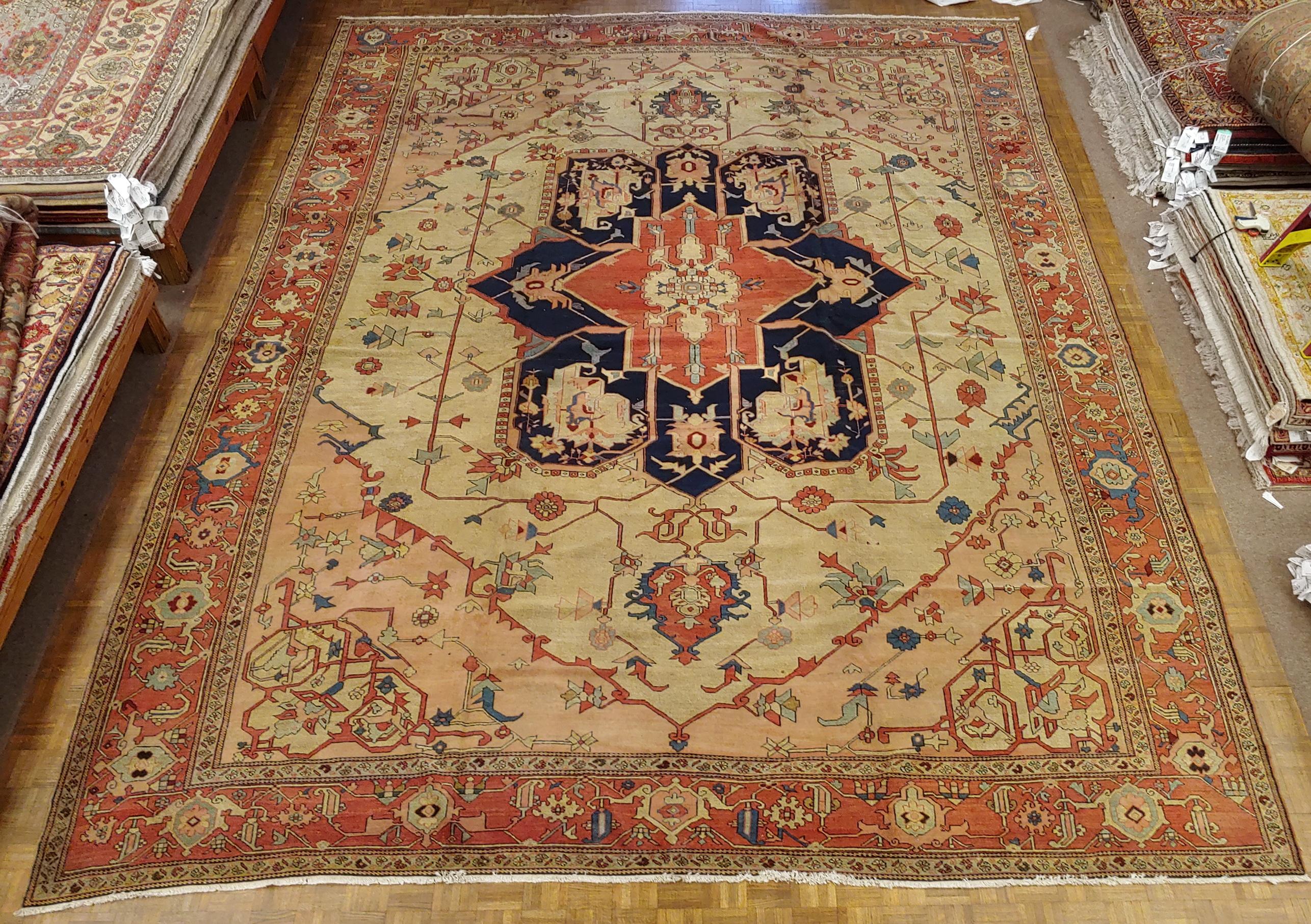 A magnificent antique Persian Serapi, which is just a very early Heriz rug, size: 11-9 x 15-3. This rug is very unusual because of the simple motif and not a lot of pattern. It has a light ivory background with salmon colored corners and a rust