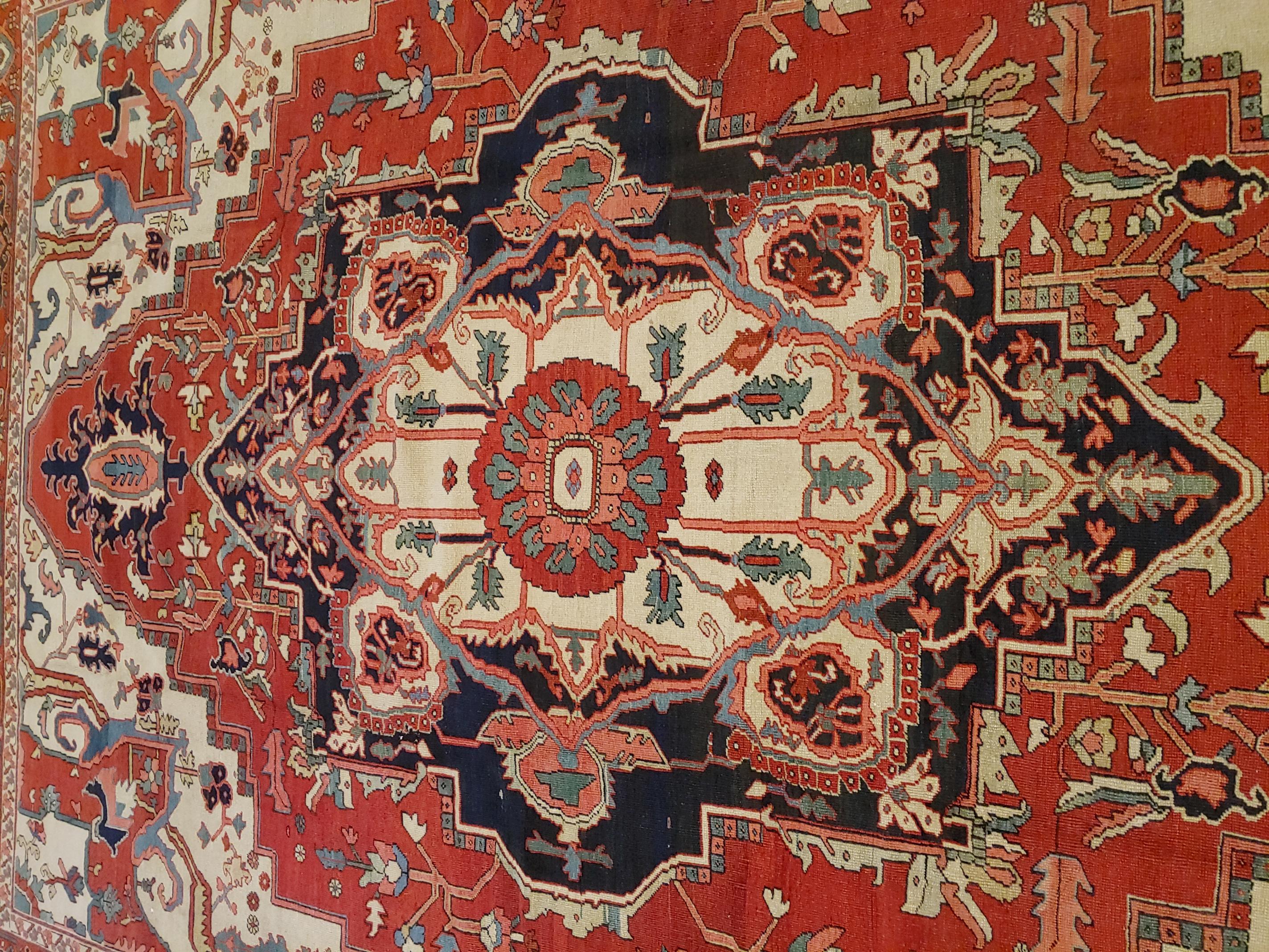 A magnificent antique Persian Serapi (early Heriz) rug, 9-2 x 11-7, room size. This rug has a red-rust background with ivory colored corners and a red-rust border.