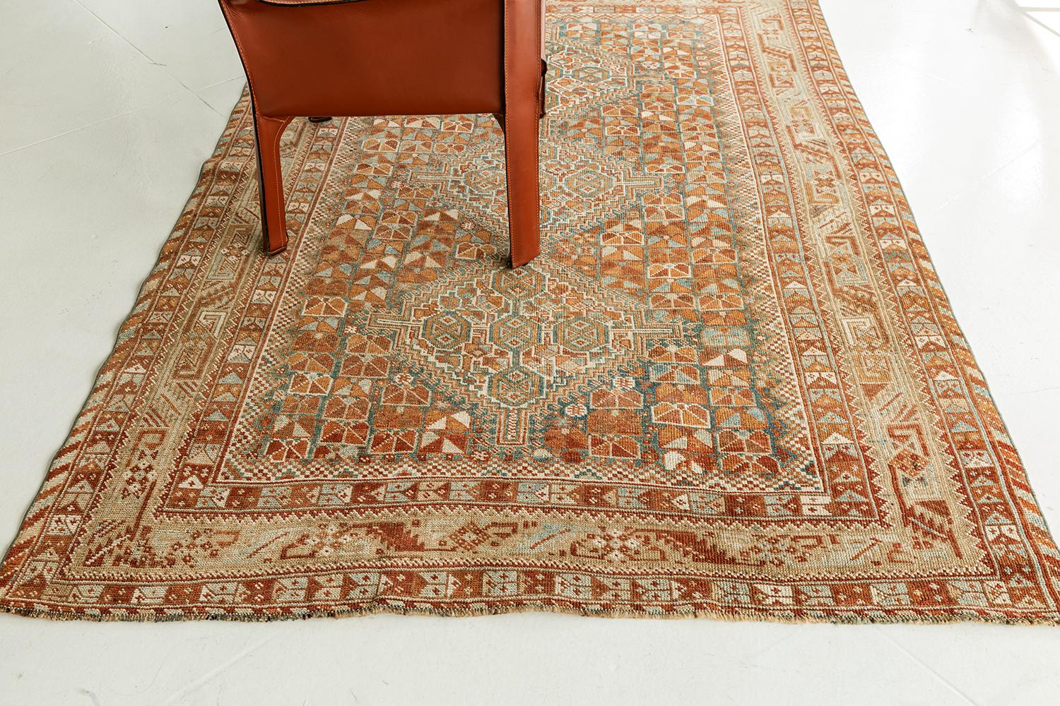 This sophisticated Antique Persian Shiraz rug from Persia features a beautiful natural wool pile. It is adorned with cinnamon, saffron, and earthy tone colors in a remarkable design. Series of three central medallions, geometrical patterns, and