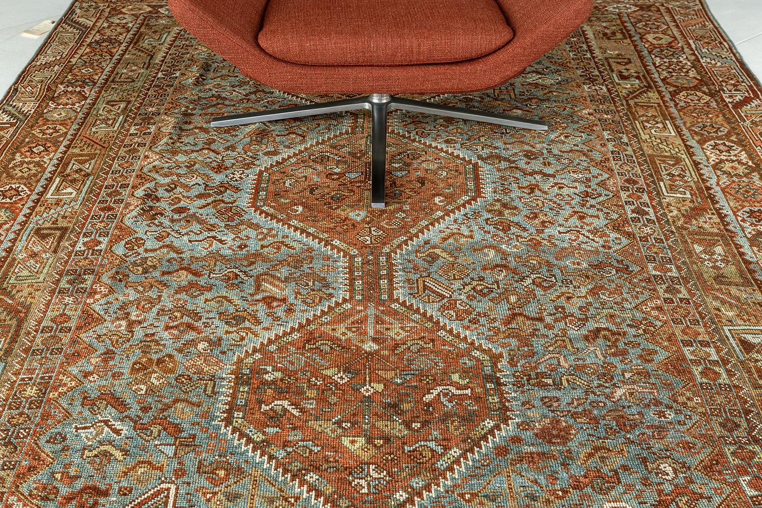 Esta sofisticada alfombra persa antigua Shiraz de Persia presenta un hermoso pelo de lana natural. Está adornado con colores canela, azafrán y tonos terrosos que conjuntan motivos, elementos floridos y símbolos. Las series de tres medallones