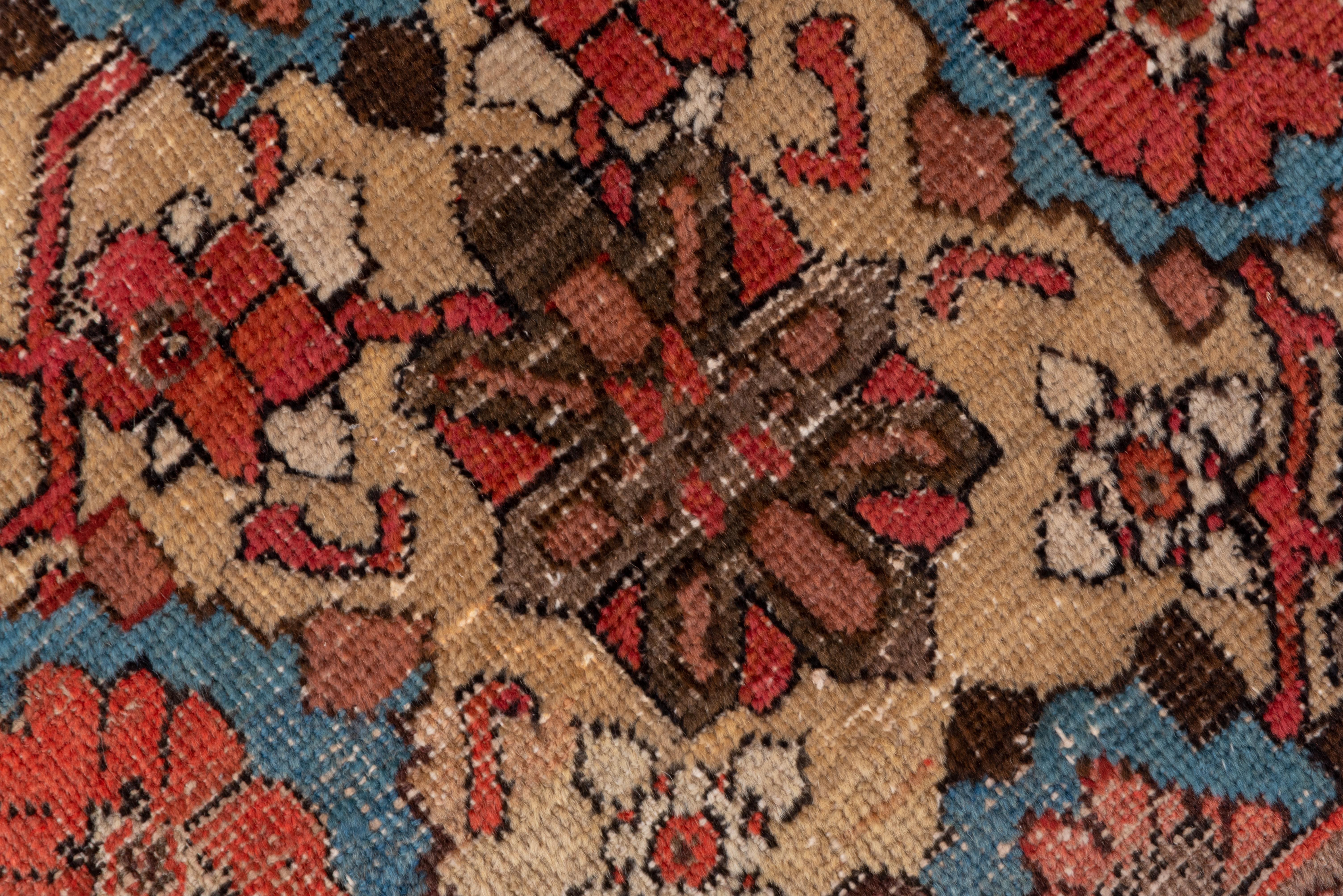 Dieser antike westpersische Dorfteppich zeigt ein ikonisches Allover-Rosettengitter von Mina Khani auf einem sandfarbenen Strohfeld mit Akzenten in Hellblau, Rot, Petrol, Rosa und Eierschale. Das Muster bewegt sich und verändert sich, anstatt starr
