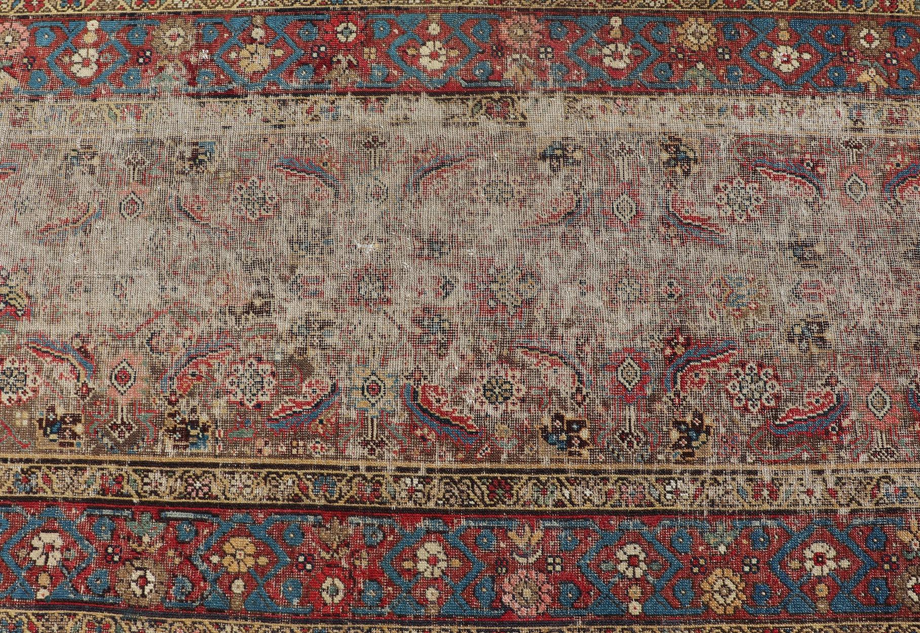 This exquisite antique hand-knotted distressed Persian Sultanabad runner features an all-over sub-geometric floral design replete in jewel tones and enclosed within a complementary, multi-tiered border; making this rug a perfect fit for a variety of
