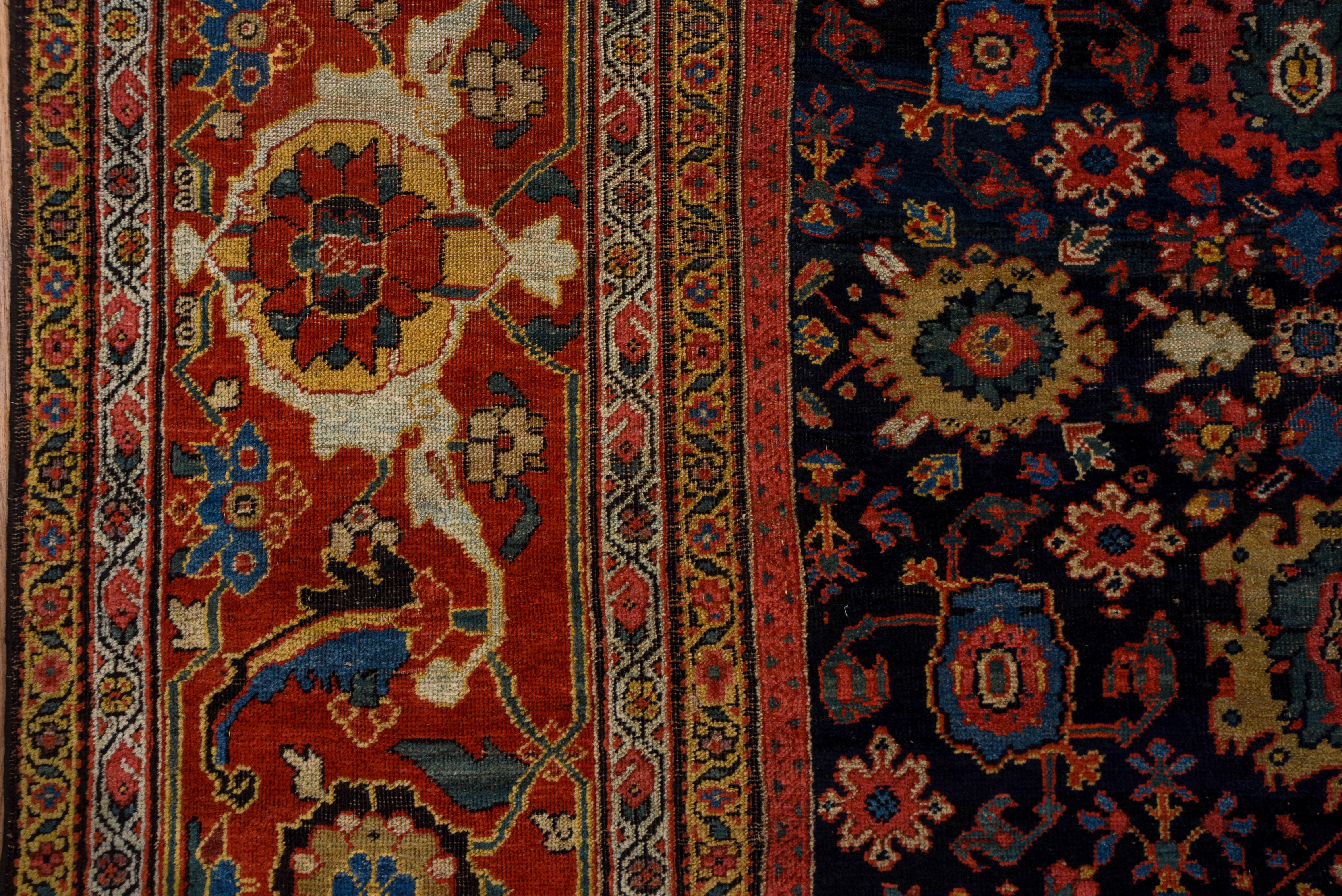 This antique west Persian rustic carpet shows a blue-black field supporting a closely rendered iconic Harshang (