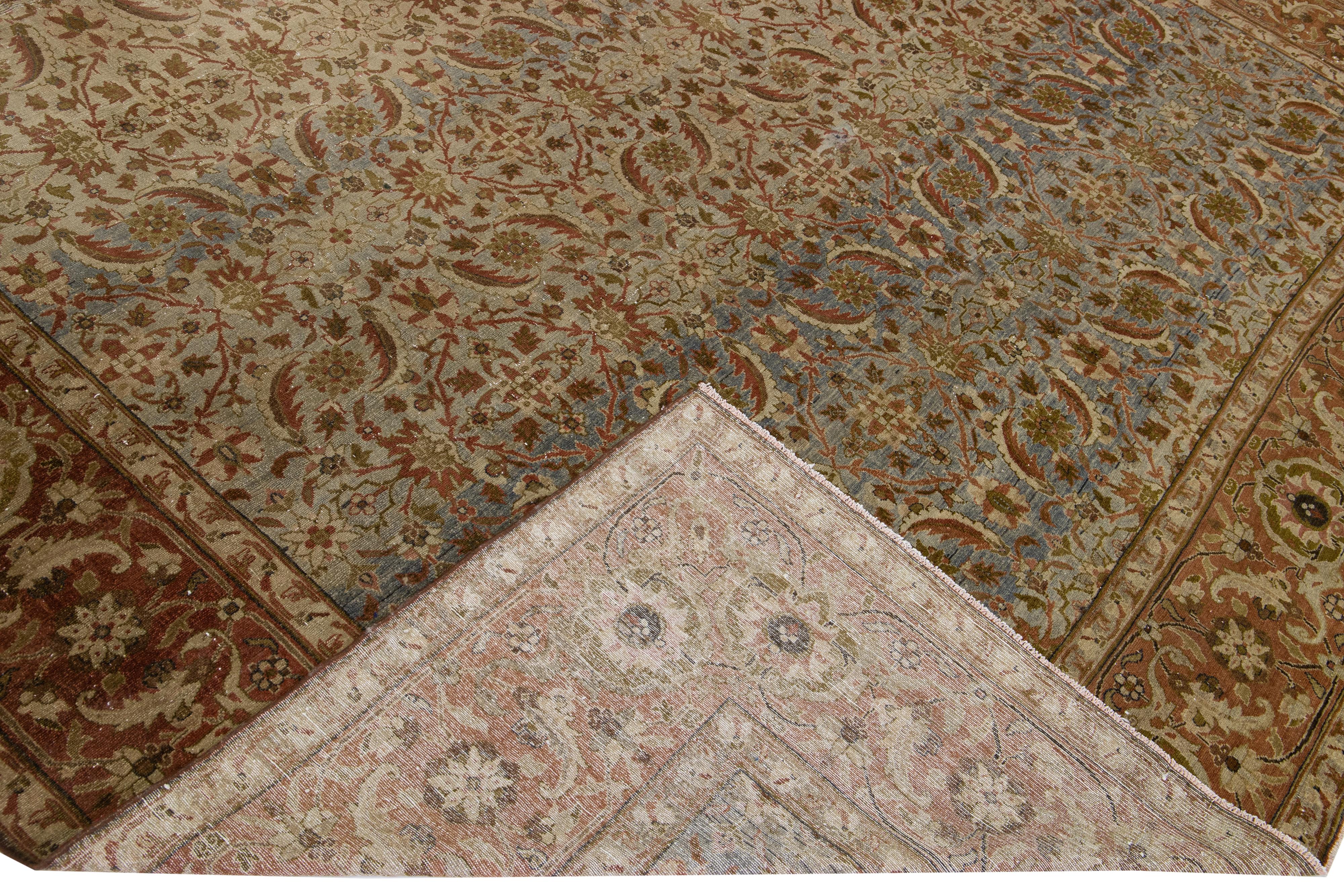 Beautiful antique Tabriz hand-knotted wool rug with a gray and tan field. This Persian piece has a designed frame with orange-rusted and green accent colors in the traditional all-over design. 

This rug measures: 11' x 16'.