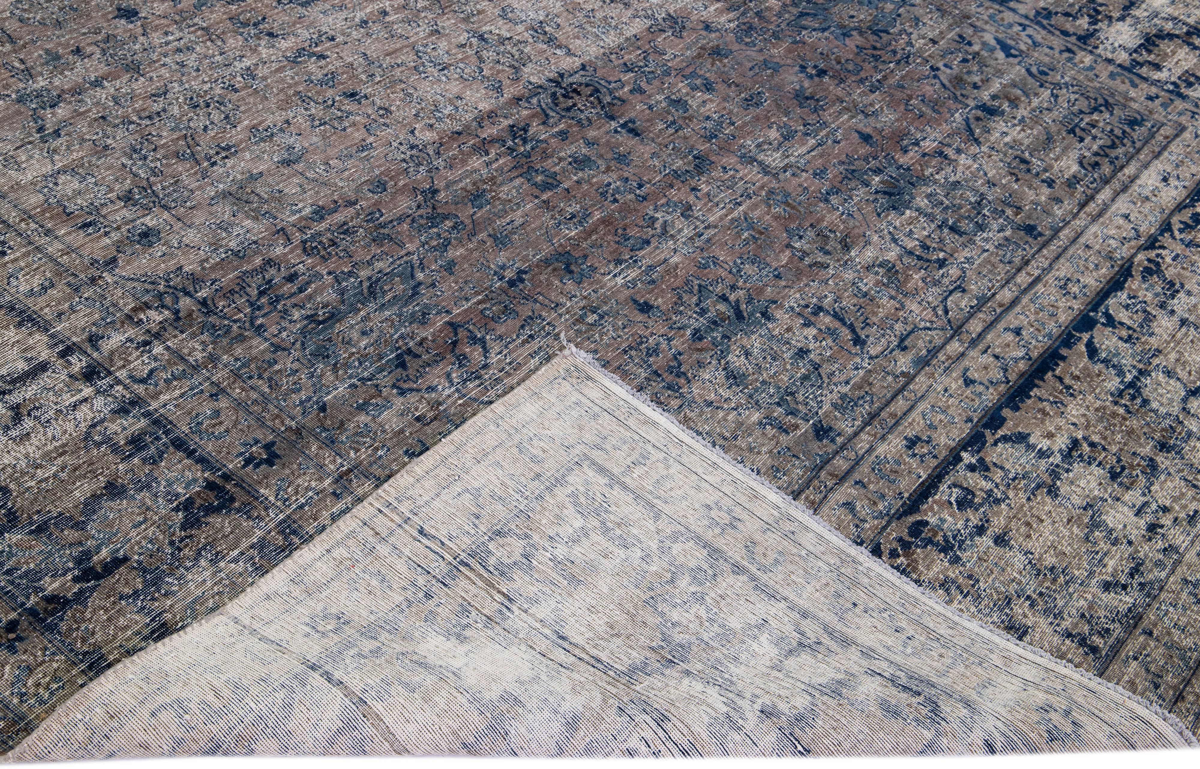 Magnifique tapis antique Tabriz en laine nouée à la main, avec un champ brun délavé. Cette pièce persane présente des accents bleus dans un magnifique motif floral intégral. 

Ce tapis mesure : 9'8