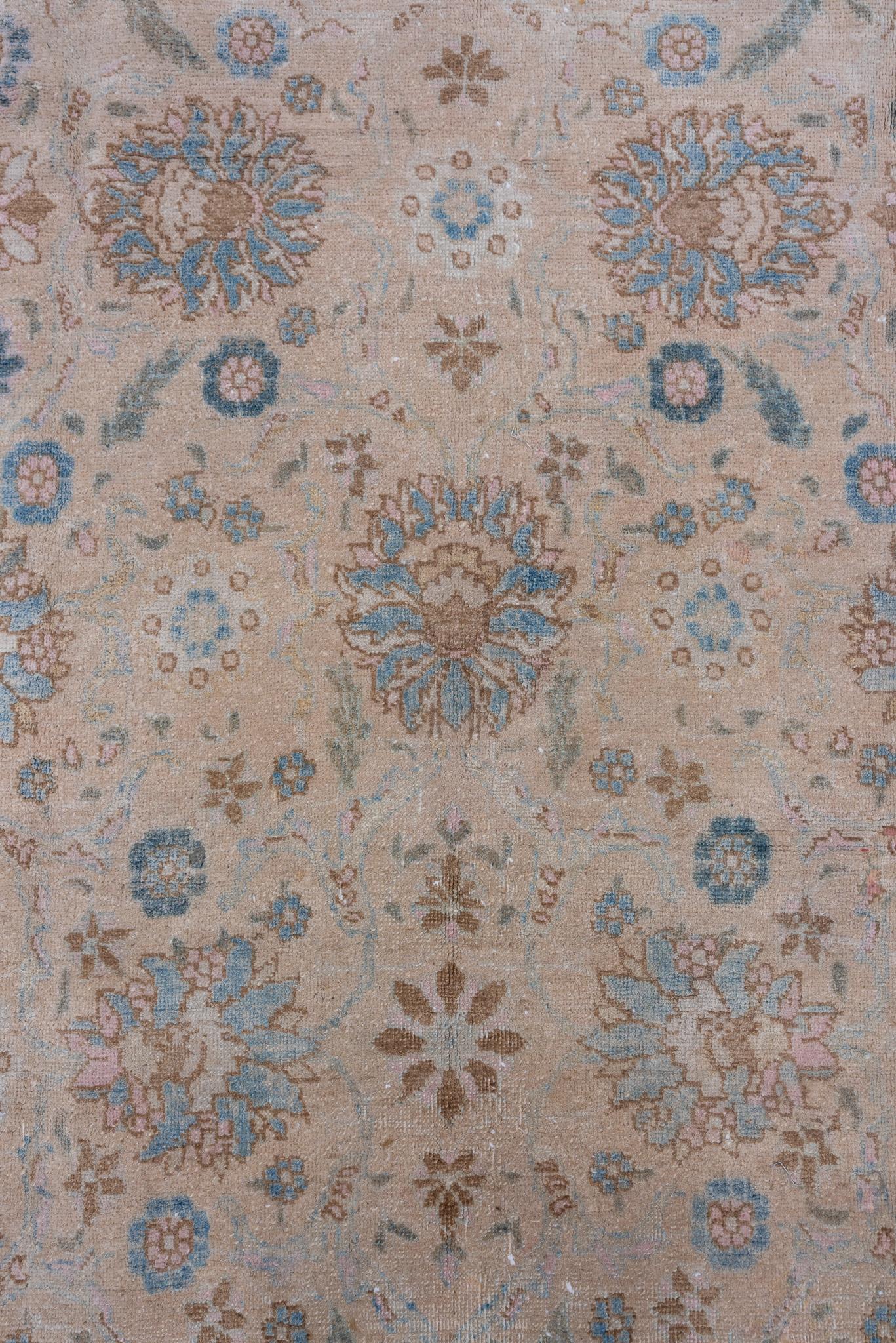 Une palette sourde de bleu et de beige caractérise ce tapis Tabriz persan ancien, qui présente un délicat motif floral. Ses couleurs subtiles et ses motifs raffinés en font une pièce polyvalente pour les intérieurs élégants.