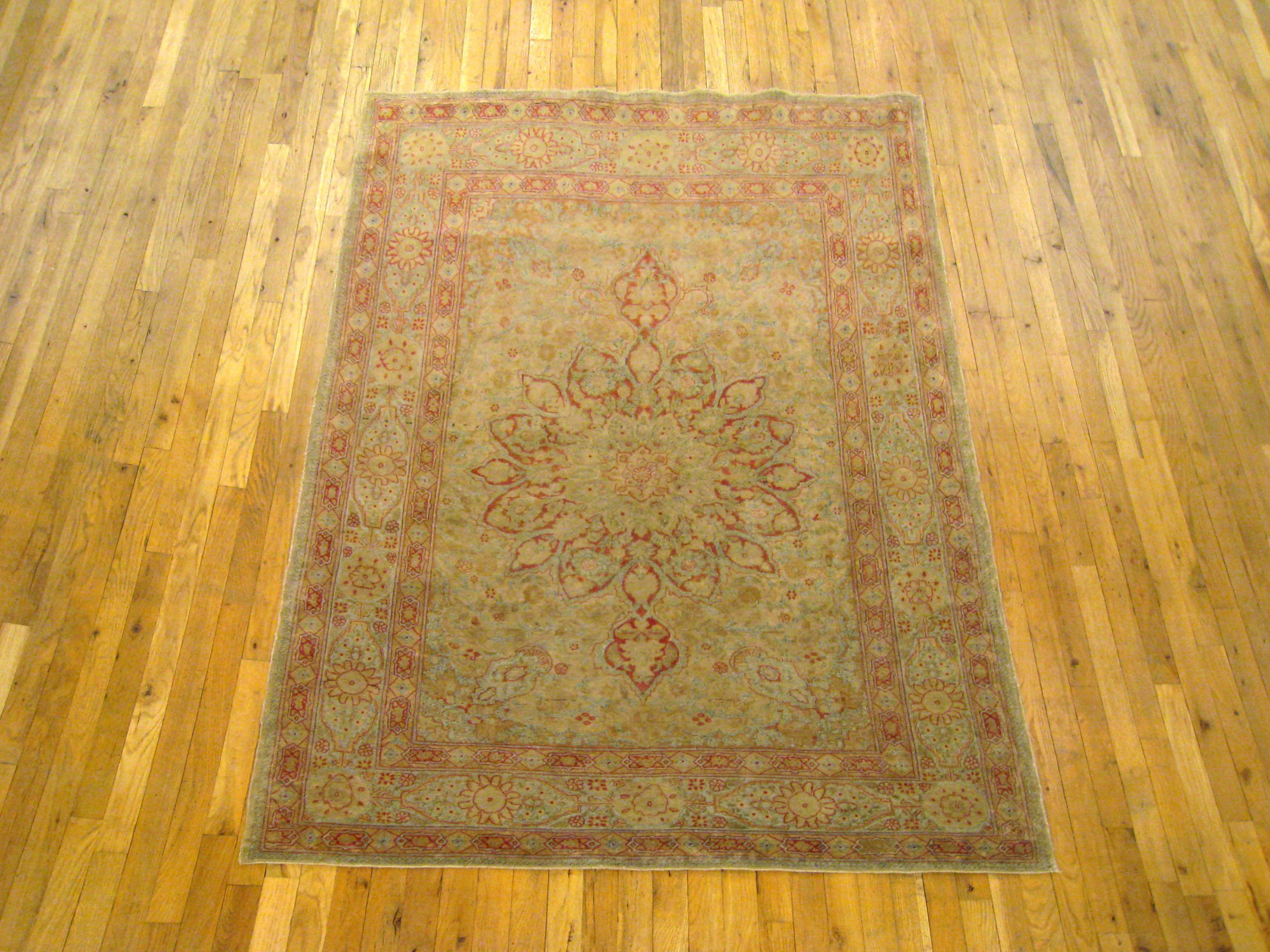 An antique Persian Tabriz oriental rug, size 6'2 H x 4'7 W, circa 1900. This handsome hand-knotted carpet features a finely rendered medallion within the central frame, and stylized floral elements in the outer borders. The color tones are soft and