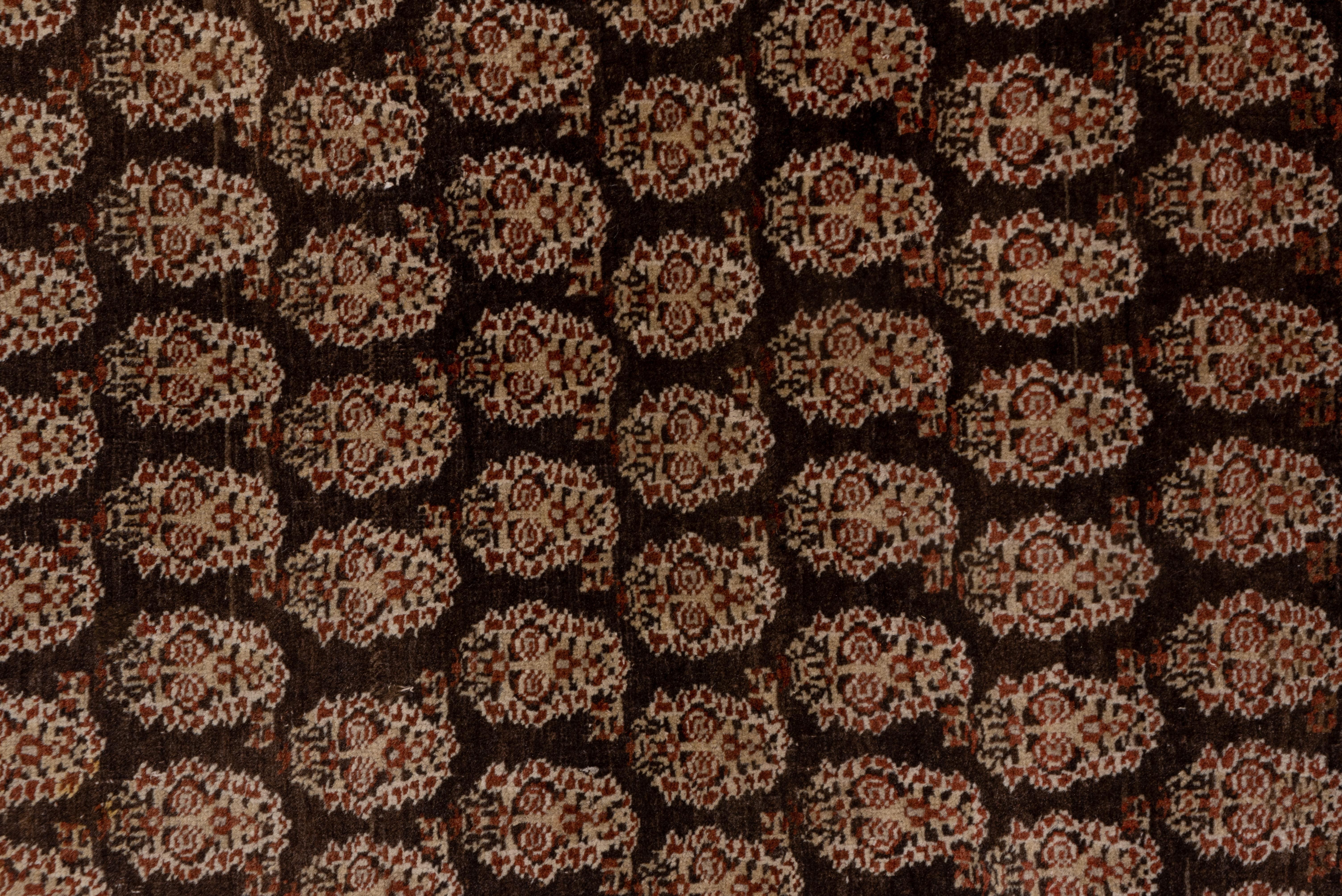 Wholly in the Saraband style, offset rows of elaborately floriated botehs switch orientation on the brick ground while the main border shows flower heads and sketch vinery sections.