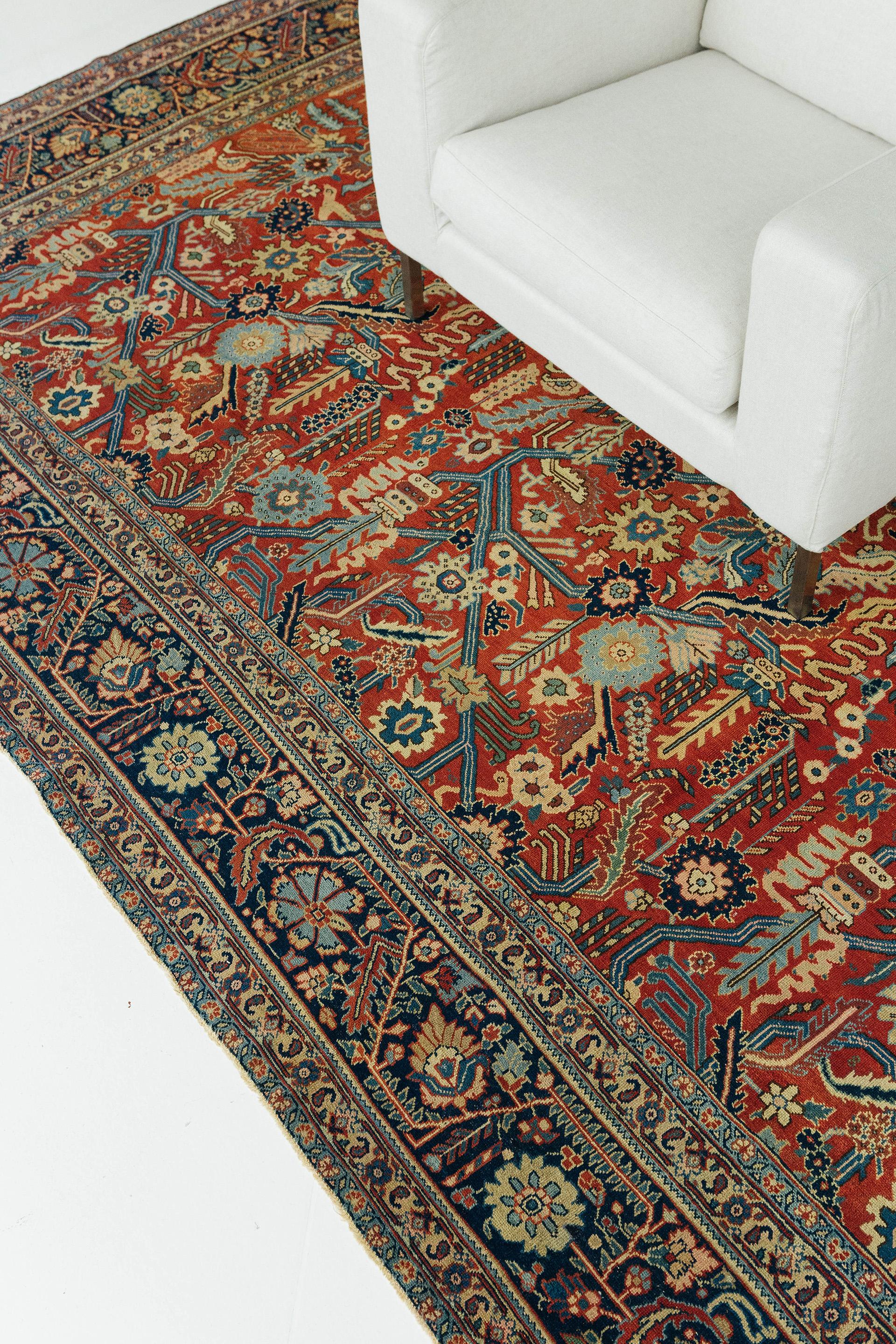 Antique Tabriz with all-over repeat, featuring a frenetic design of intertwined motifs including angular vines, palmettes, serrated leaves, rosettes, and snakes. Strong vibrant colors include cherry red field ground, dark blue border, and motif