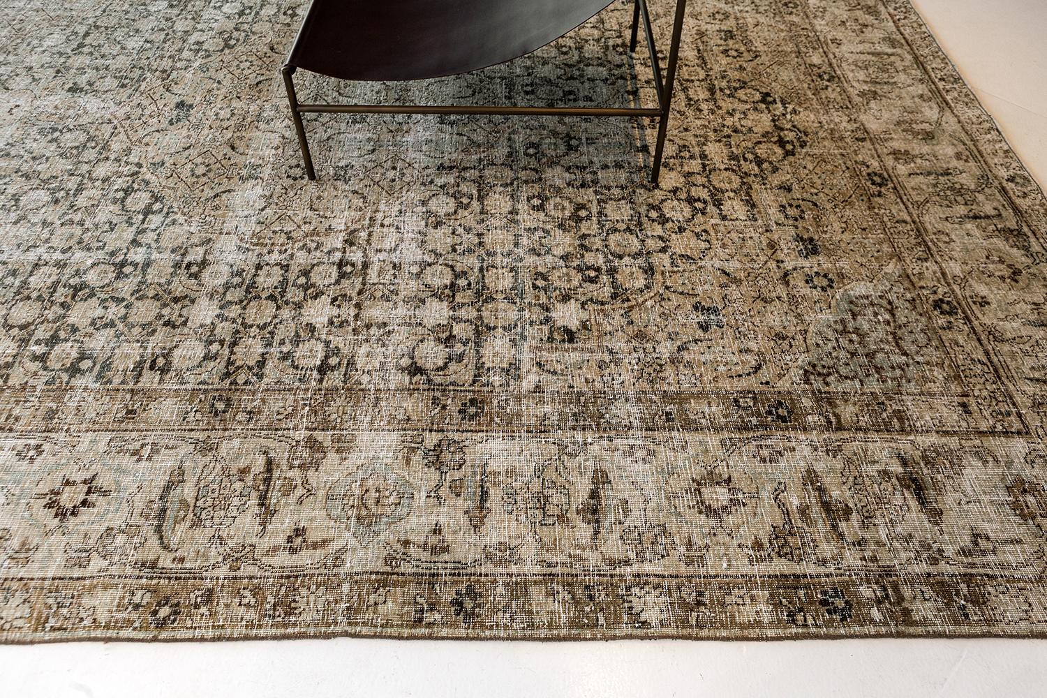 A sophisticated vintage Tabriz rug that features a central floral medallion in a series of florid patterns captivate the beauty of this masterpiece. Repetitive floral patterns in the border are outlined with symmetrical patterns of leafy tendrils.