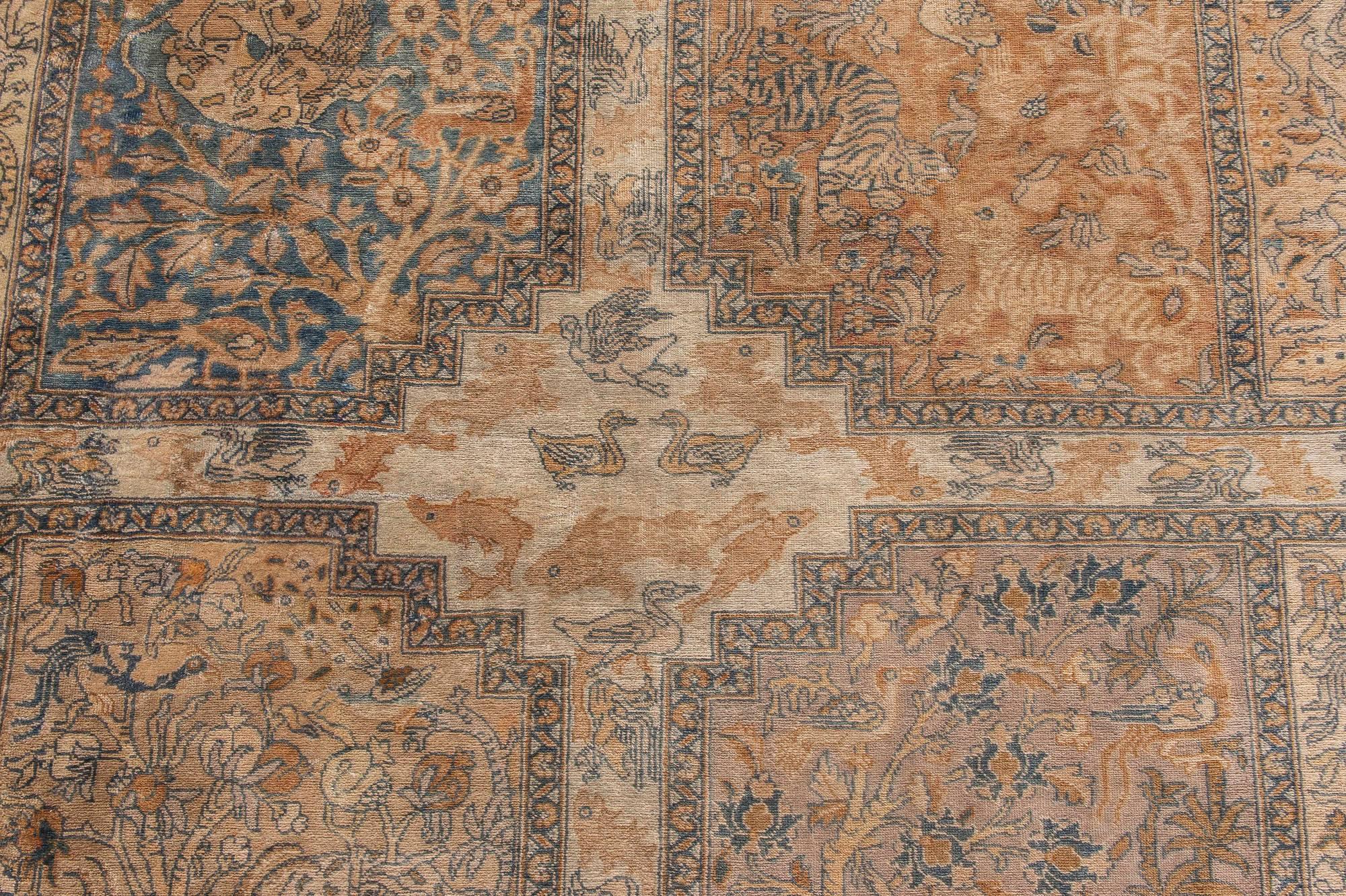 An early 20th century Persian Tabriz antique garden carpet, with an overall design of rectangular panels containing flora and fauna in shades of beige, ochre and green within a lush border of exotic trees.