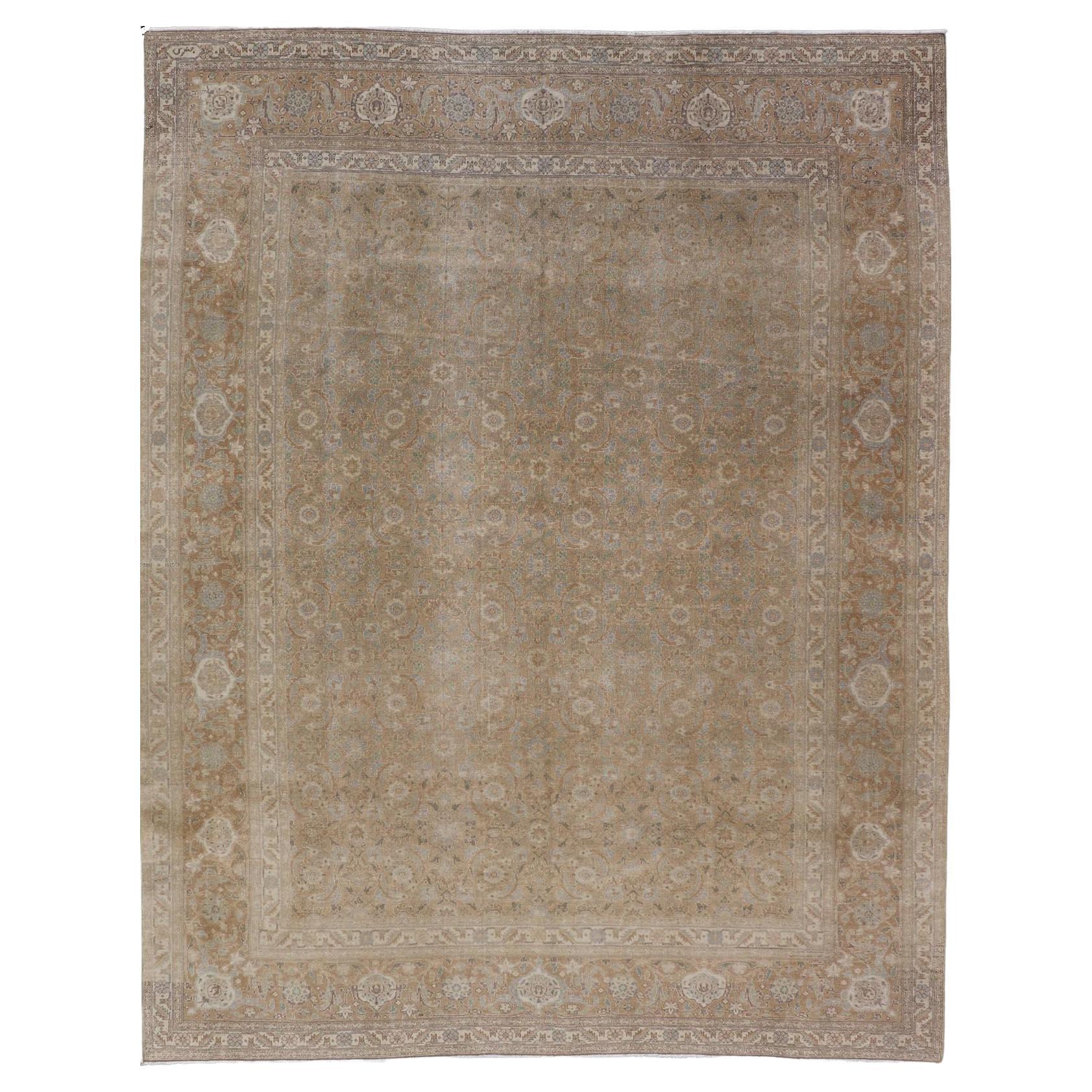 Tapis persan ancien de Tabriz en laine avec motif floral sur toute sa surface aux couleurs de la terre