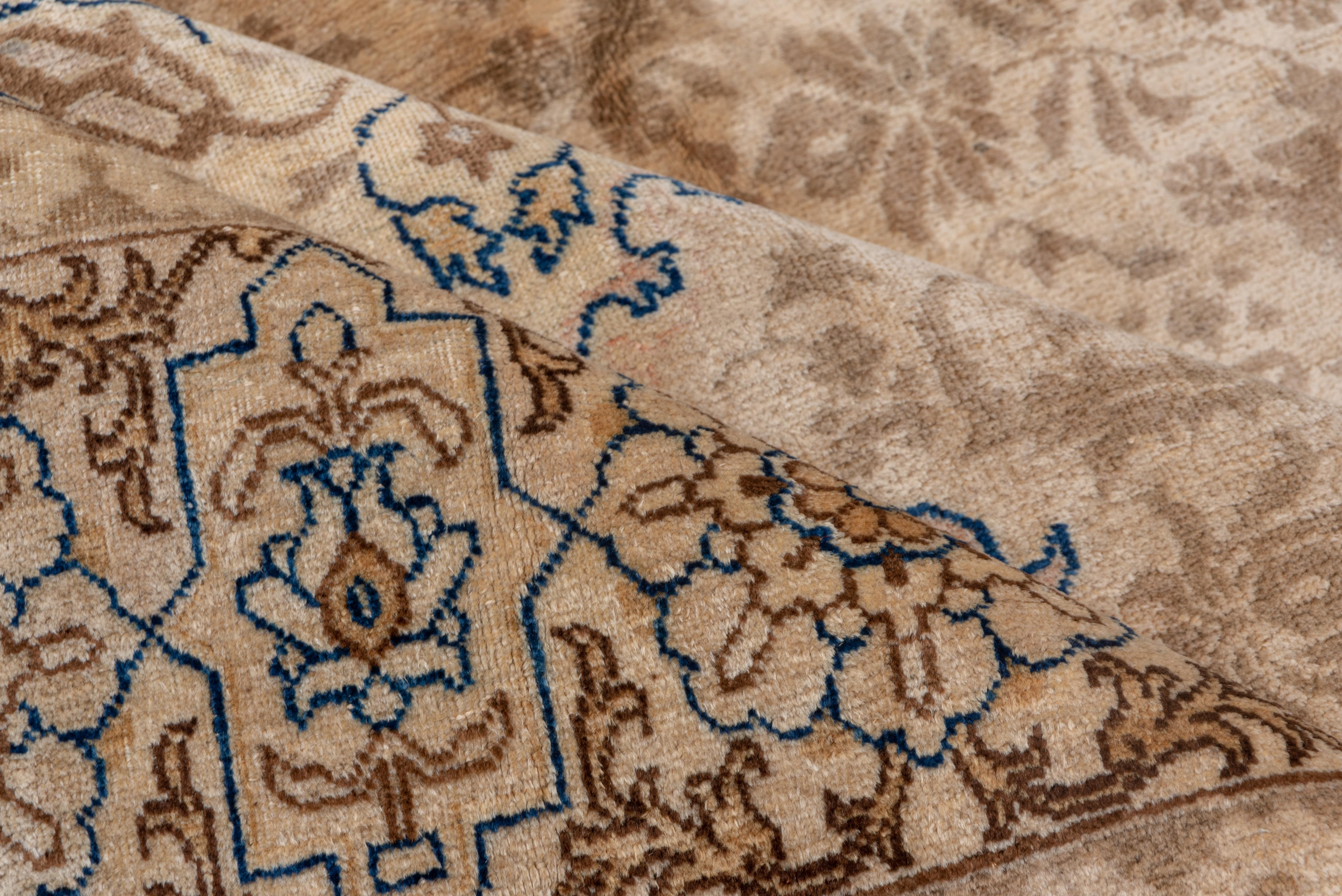 The sandy field features two stacked flame-edge medallions enclosing four outline palmettes, with half and quarter outline octogrammes. A light brown floral pattern pervades the ground. Cartouche and layered rosette cream border. Well woven, brisk