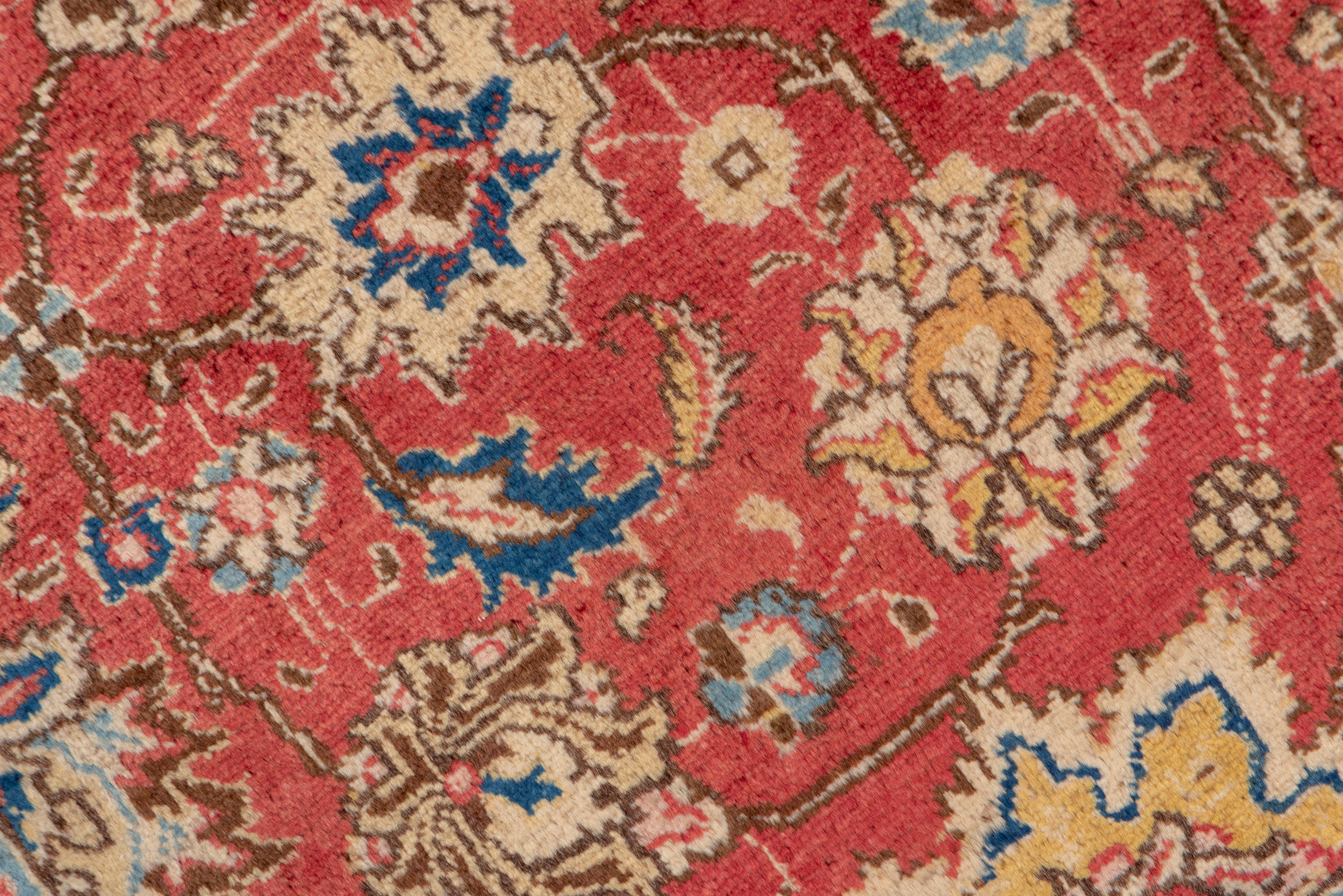 The allover palmette and vinery pattern is a Tabriz standby, and here it is precisely executed on a red ground, with an allover distribution of palmettes, larger eight-petal medallions, and densely layered arabesque vines. Straw strip-style border