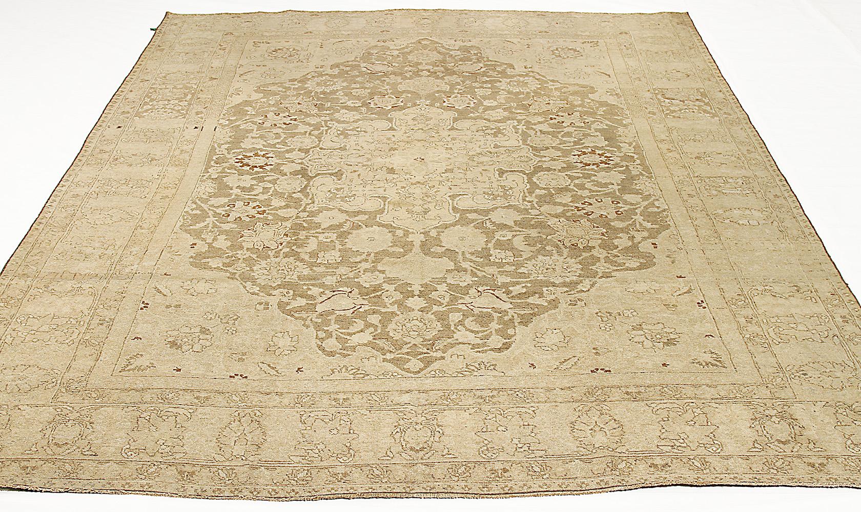 Antique Persian rug handwoven from the finest sheep’s wool and colored with all-natural vegetable dyes that are safe for humans and pets. It’s a traditional Tabriz weaving featuring a large floral medallion in beige with shades of brown over an