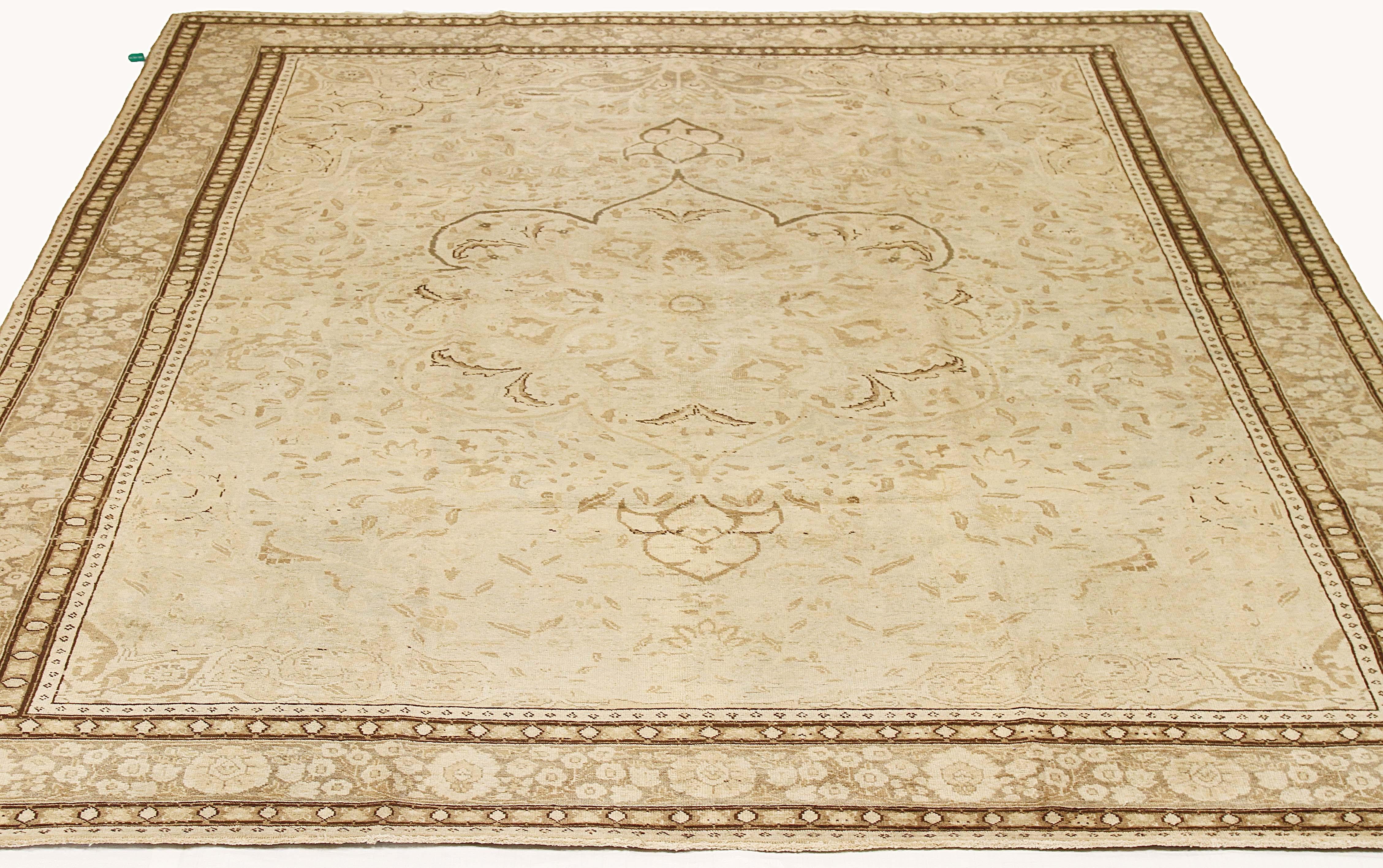Antique Persian rug handwoven from the finest sheep’s wool and colored with all-natural vegetable dyes that are safe for humans and pets. It’s a traditional Tabriz weaving featuring brown and gray floral details over an ivory field. It’s a stunning