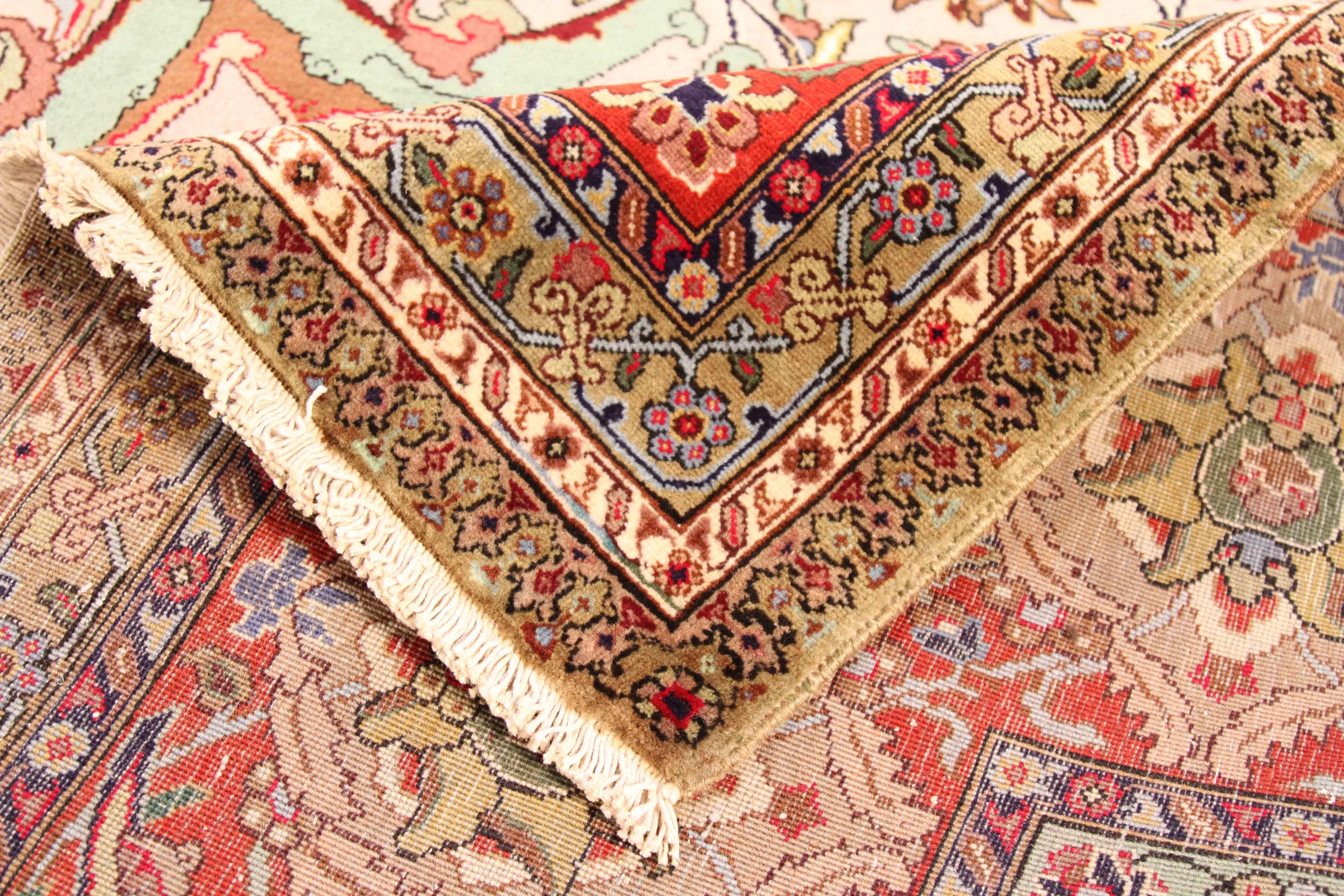 Antique Persian rug created in the 1960s by handweaving fine wool and coloring it with rich organic dyes. The design pattern featured on its field is an incredible mix of floral details in ivory, red and pink. It’s a style that has made Persian rugs