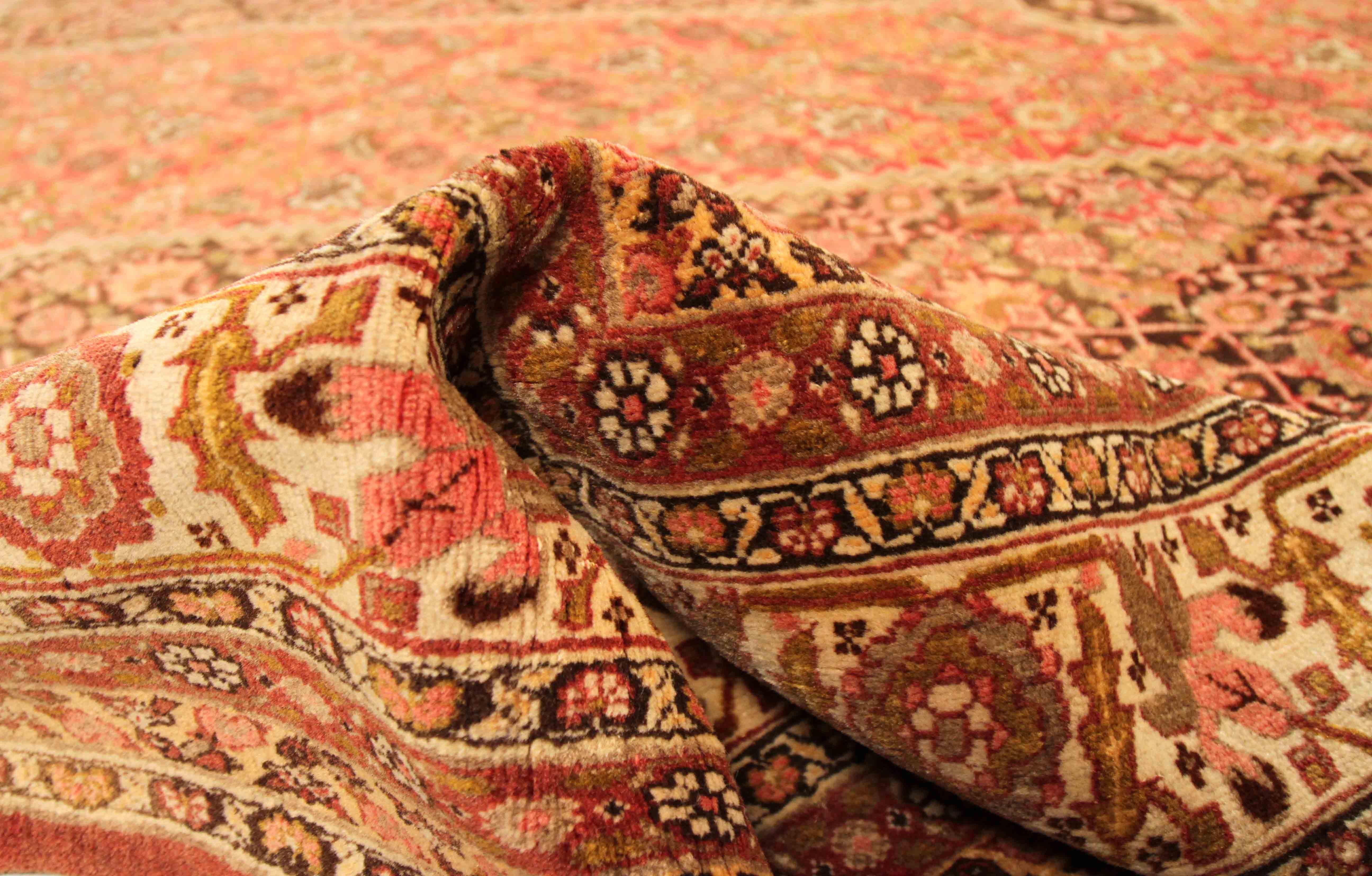 Antique Persian rug handmade in the 1910s. Crafted with the highest quality of wool and colorful vegetable dyes that are 100% organic. It features large diamond patterns filled with floral details in black, red, and ivory. It’s a Tabriz weave which