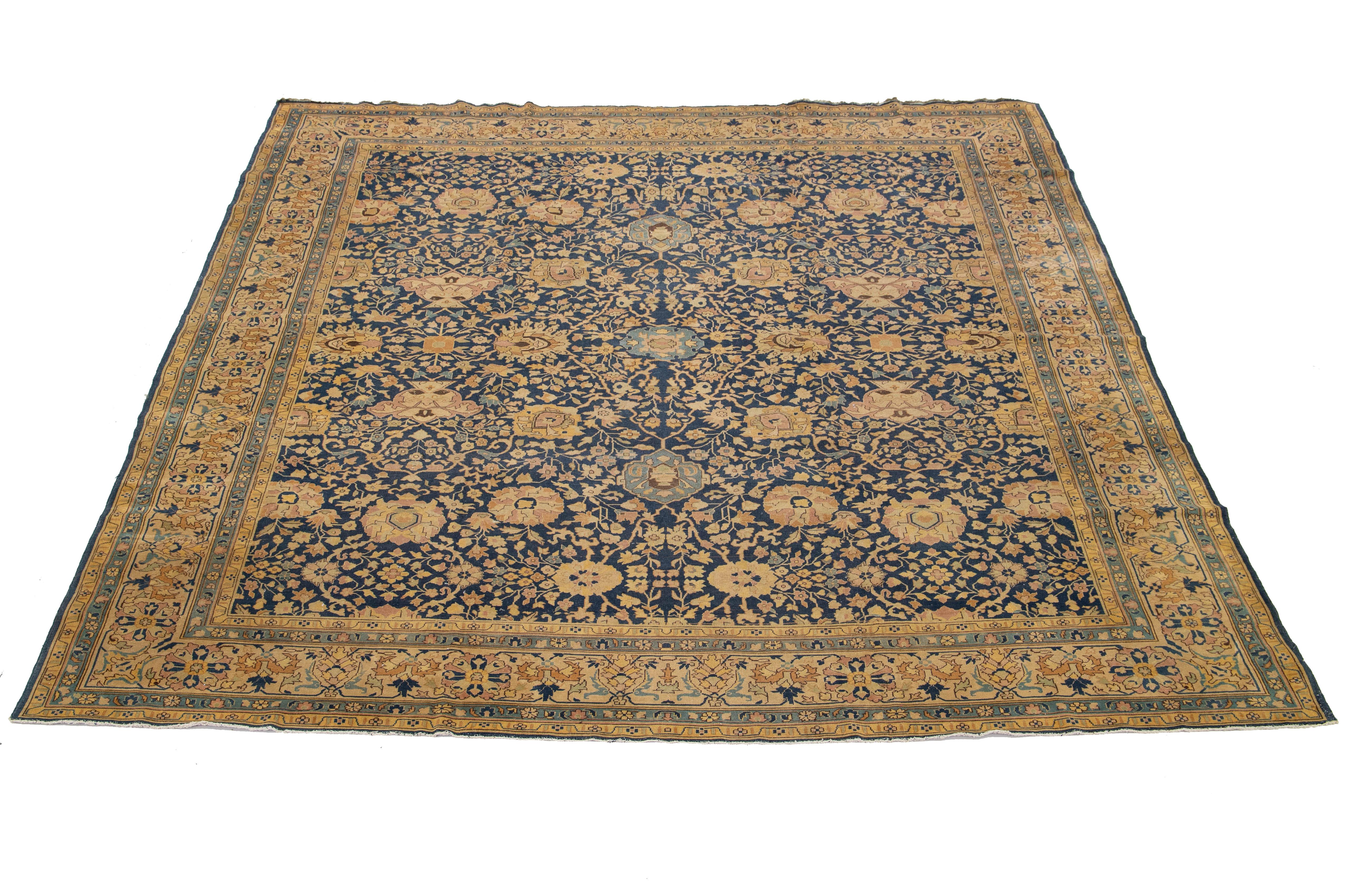 Dieser antike persische Täbriz-Teppich aus den 1880er Jahren zeichnet sich durch ein auffälliges dunkelblaues Feld aus, das mit einem bezaubernden floralen Allover-Muster verziert ist. Das Design wird durch zarte gelbe, grüne, blassrote und